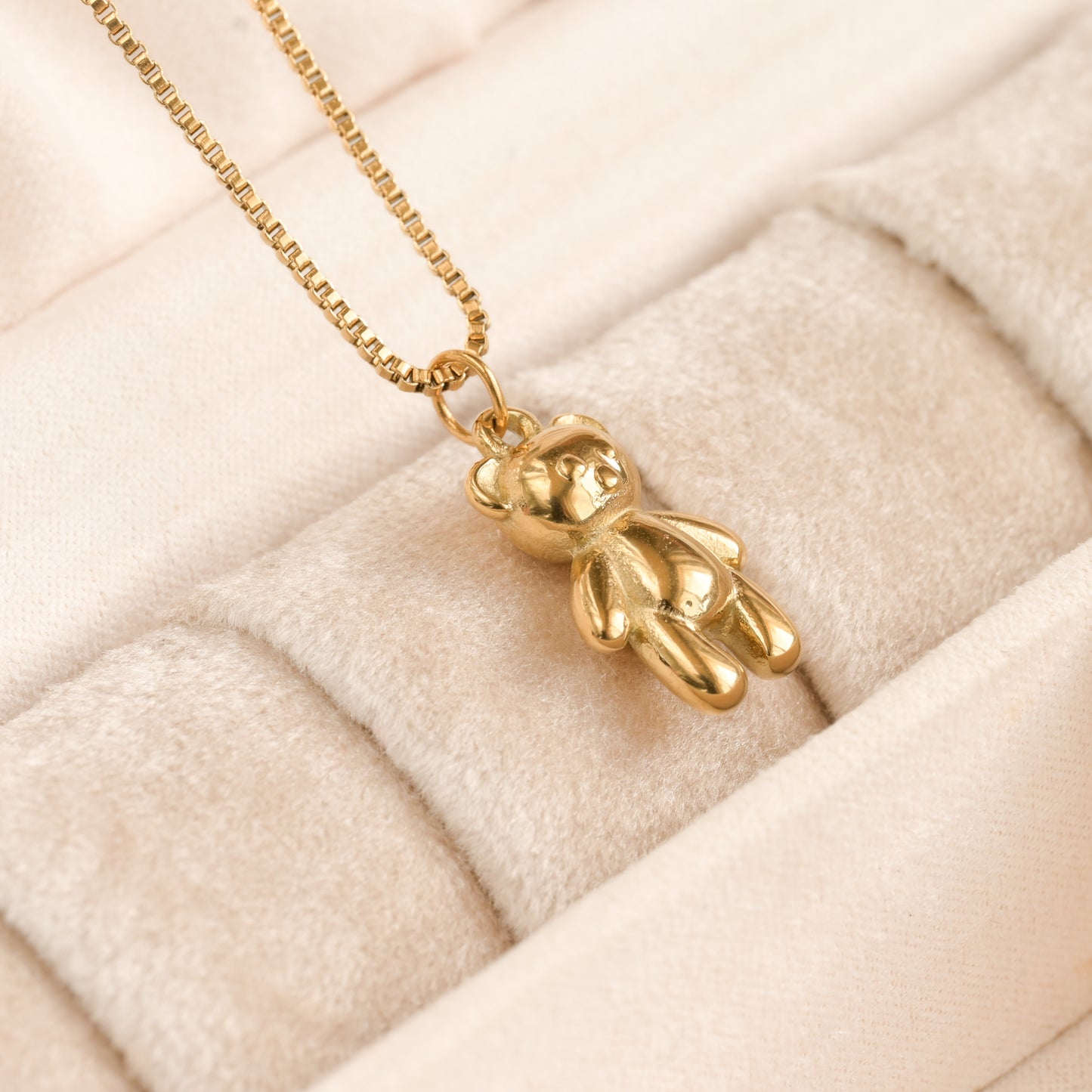 18k gold pear pendant flat on a velvet jewelry box hanging from a delivate box chain.