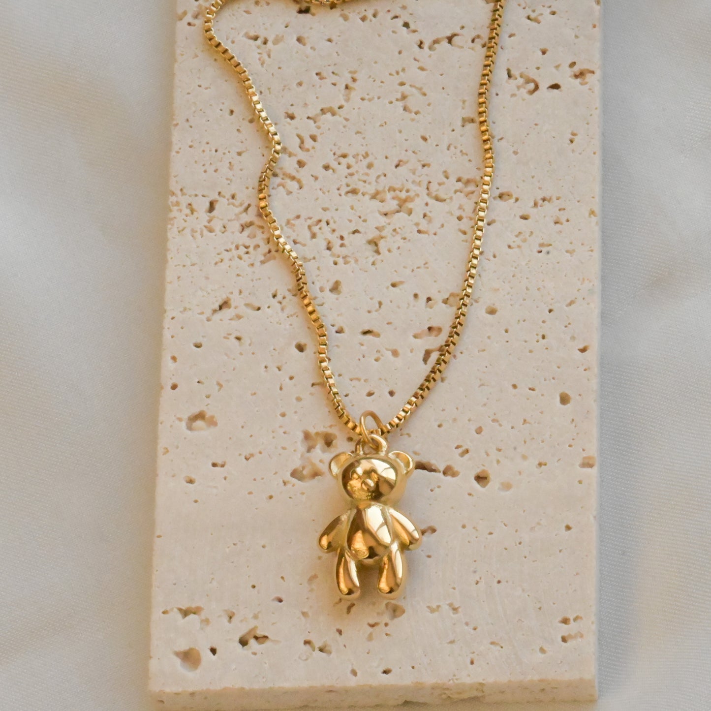 top view of the necklace on a textured beige stone surface