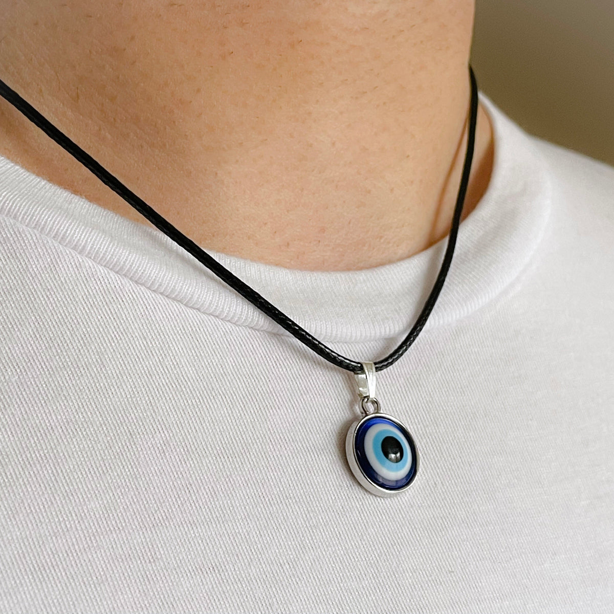 Necklace with an eye-shaped pendant worn by a man on a plain background