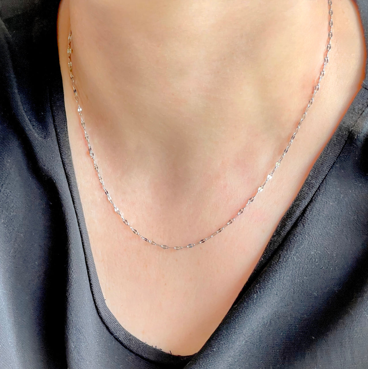 Silver mariner chain necklace on a person wearing a black top