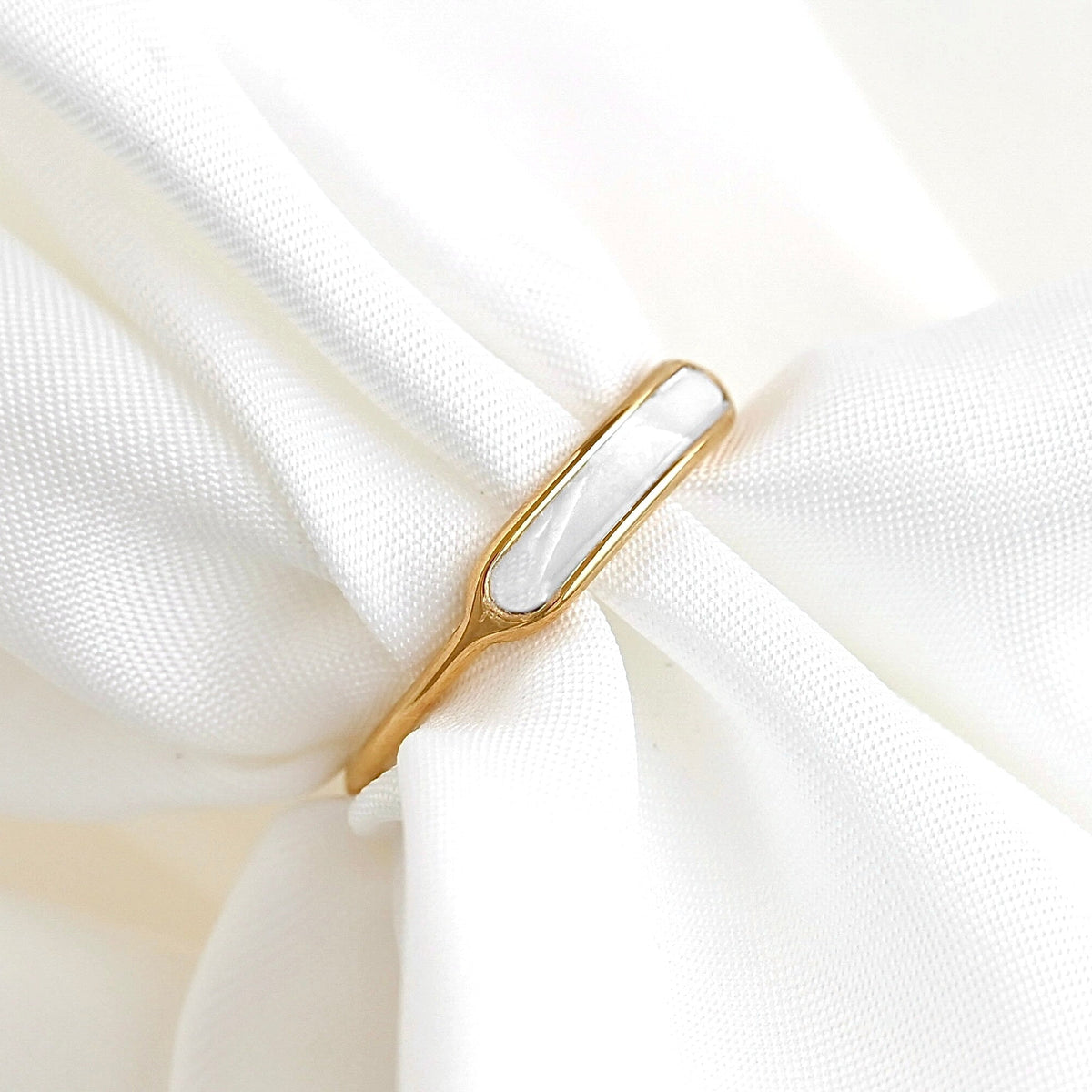 Dainty gold ring with mother of pearl inlay on white fabric