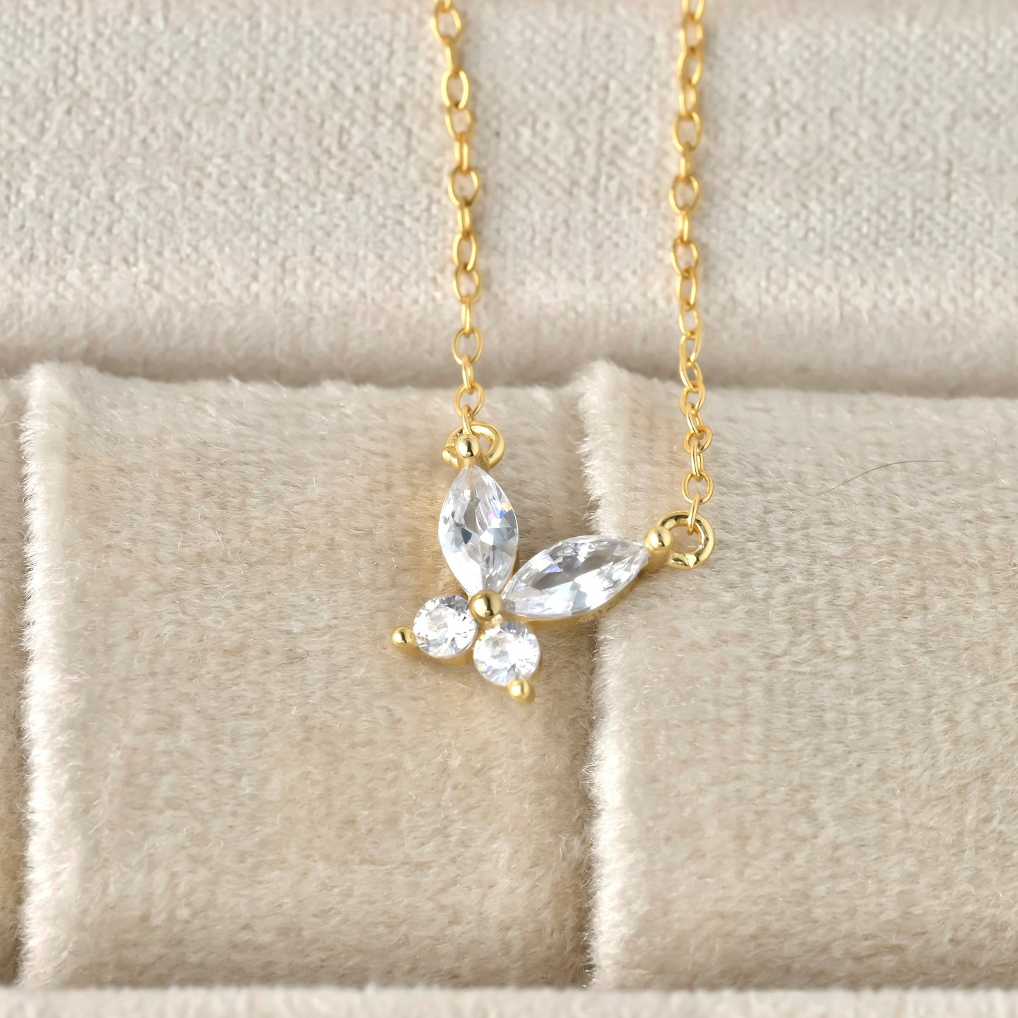 close up view of cz butterfly pendant on a soft beige fabric background