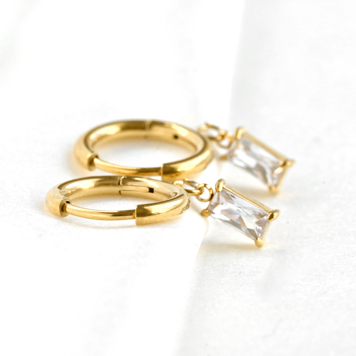 Gold hoop earrings with baguette cut stones on a white background