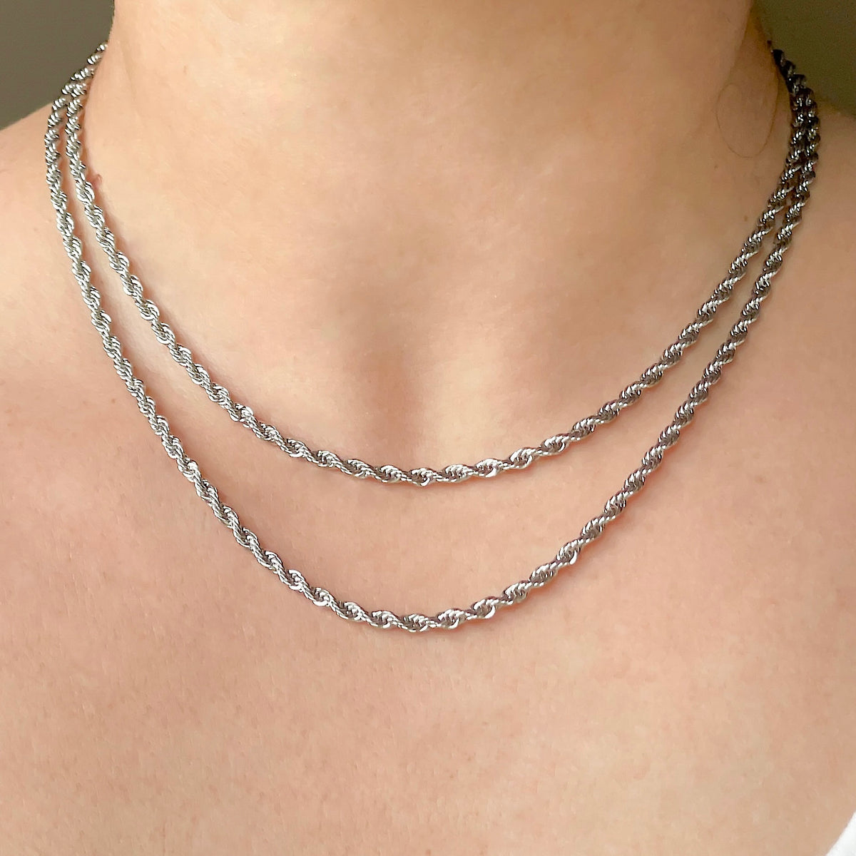Two 3mm silver rope chains layered on a person's neck against a neutral background