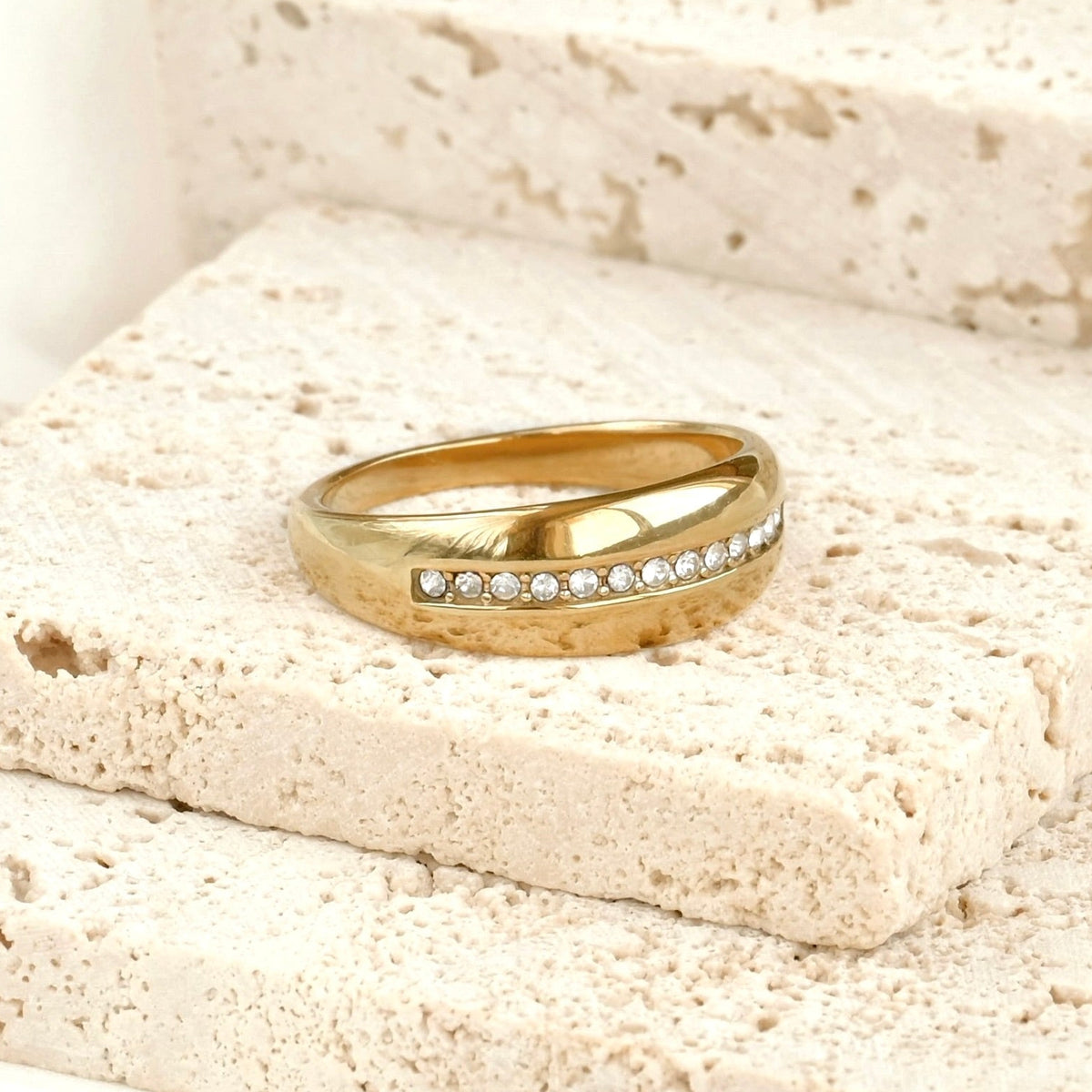 Thick gold ring with CZ line on a textured stone surface