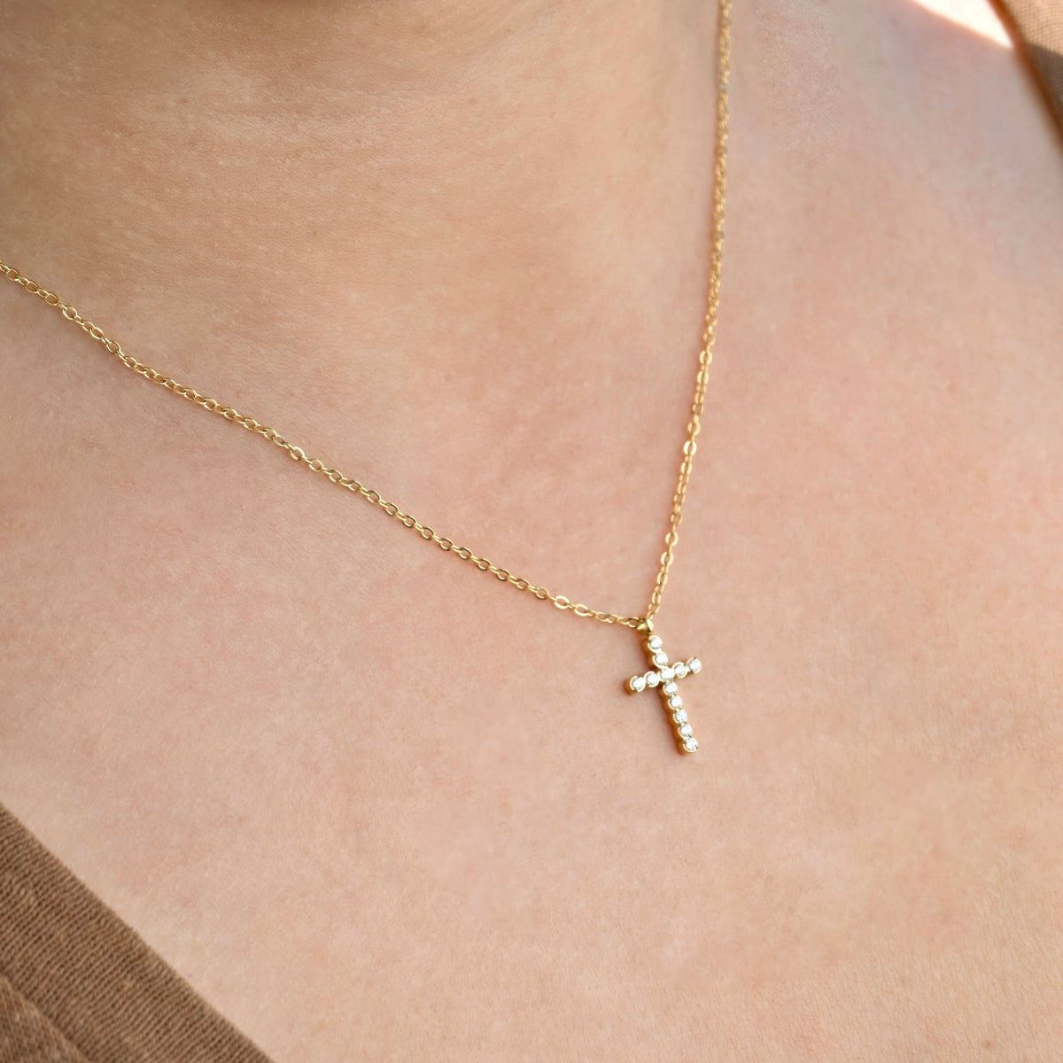Side view of gold necklace with a CZ cross pendant on a person's neck
