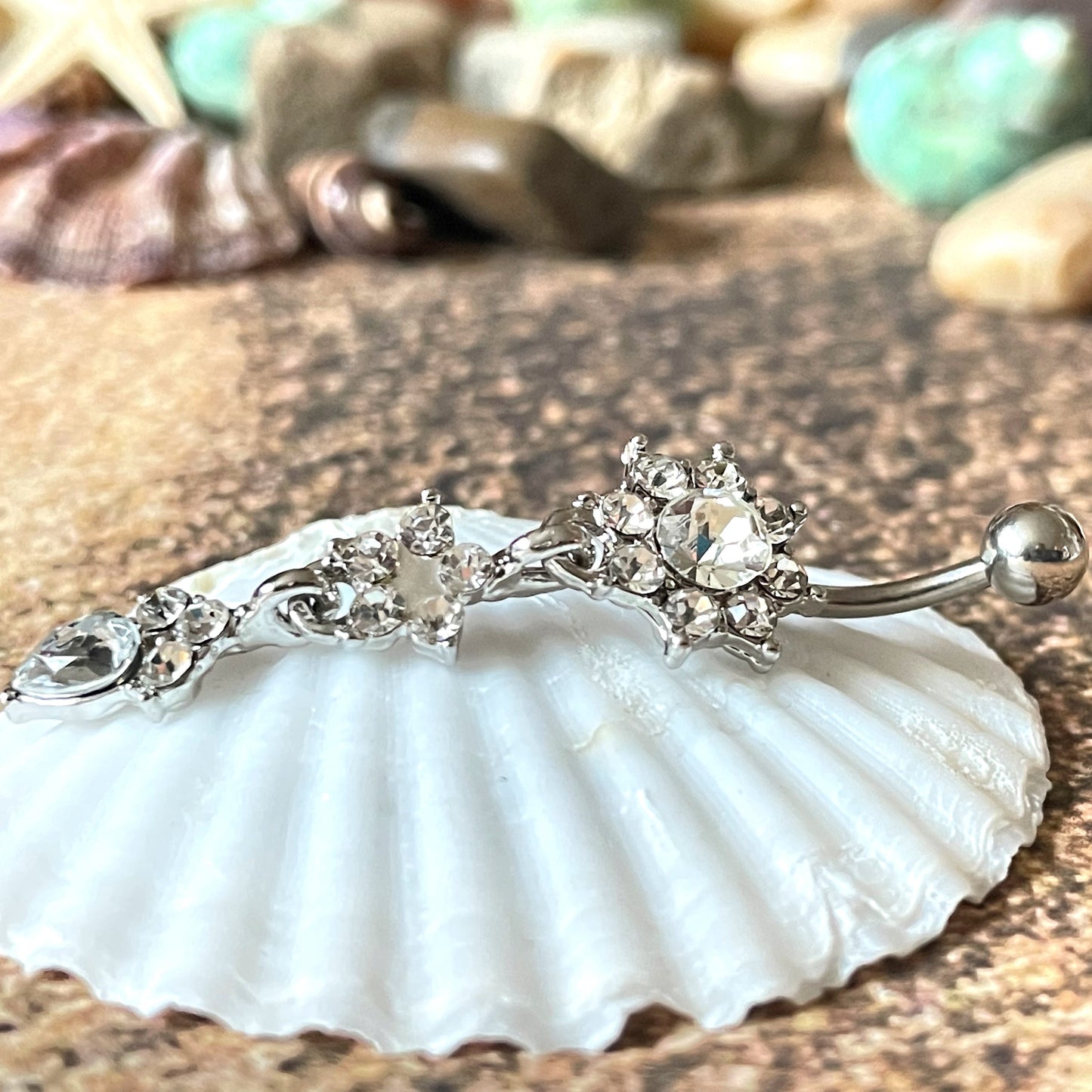 Decorative belly button ring on a seashell with a natural stone background