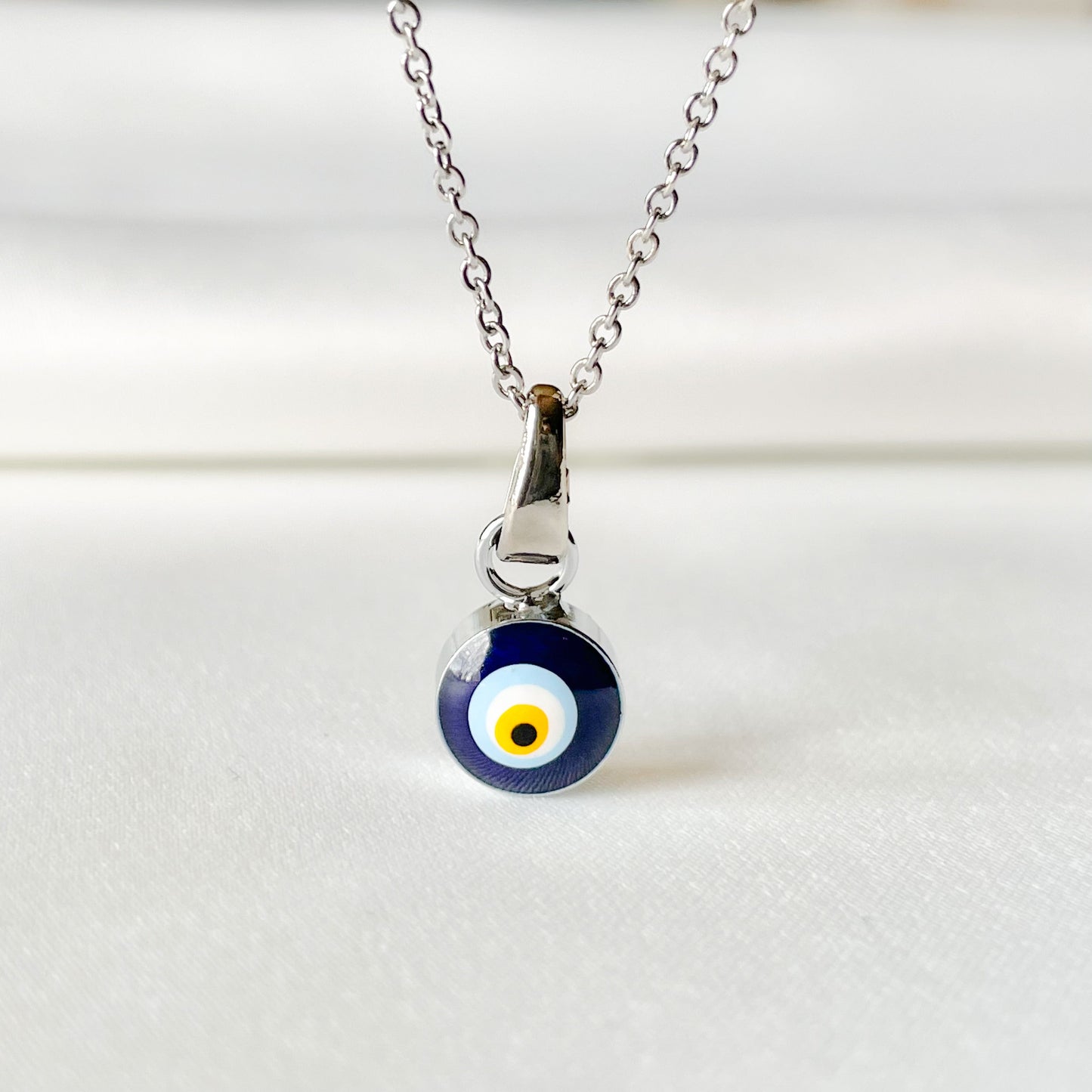 Necklace with a small round enamel pendant on a white background