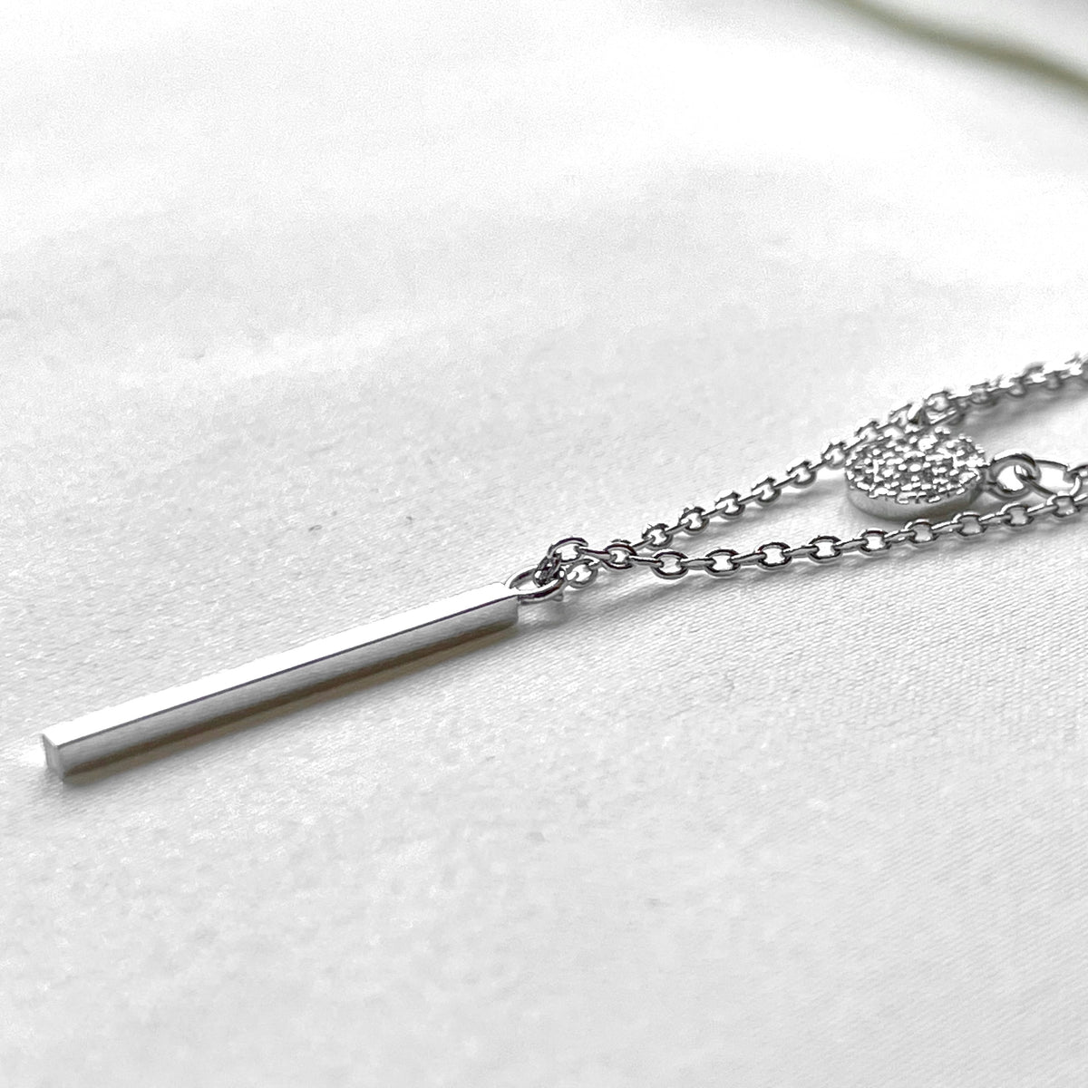 Side view of silver bar necklace on a white background