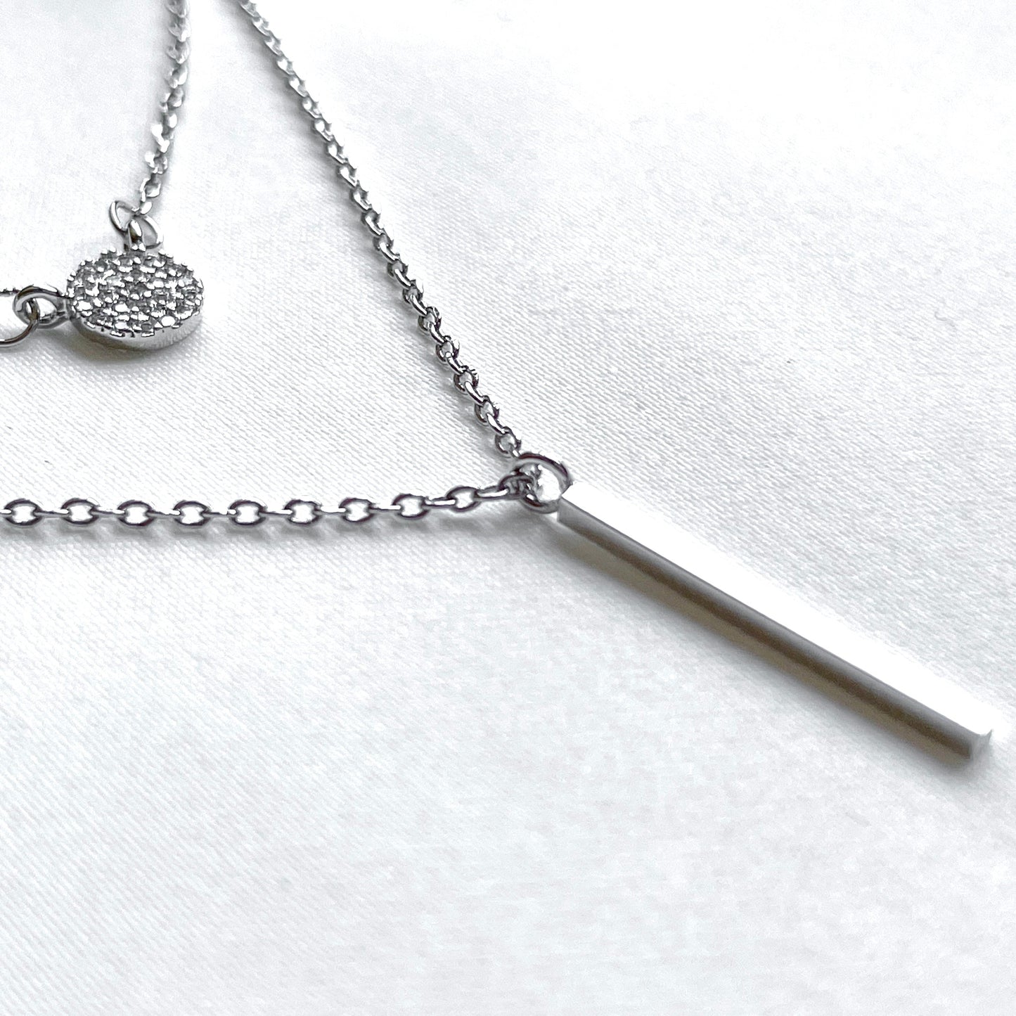 Silver necklace with a bar pendant on a white background