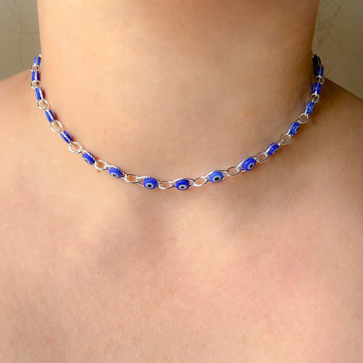 Front view of person wearing a silver necklace with blue eye-shaped beads