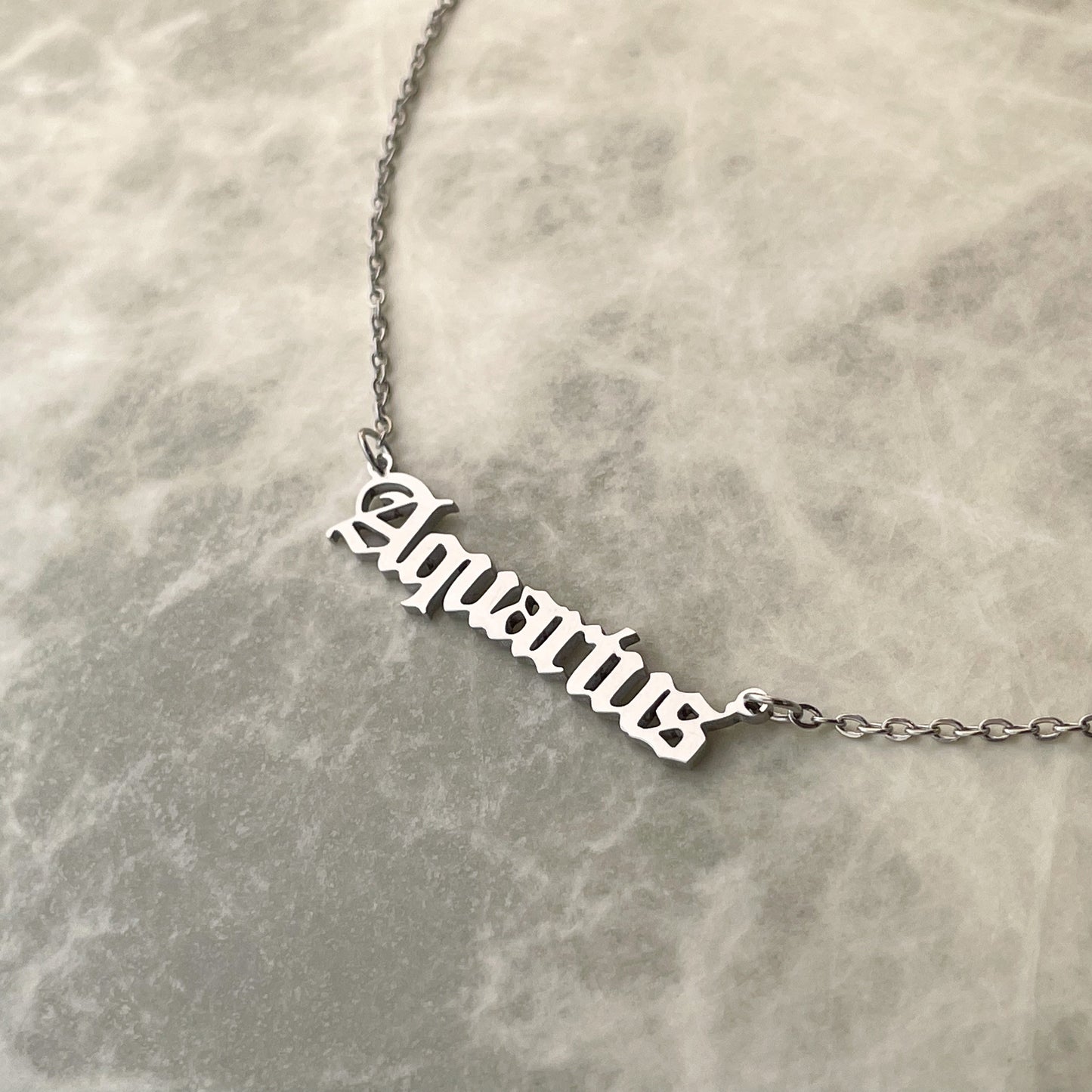 Silver 'Aquarius' necklace on a marble surface