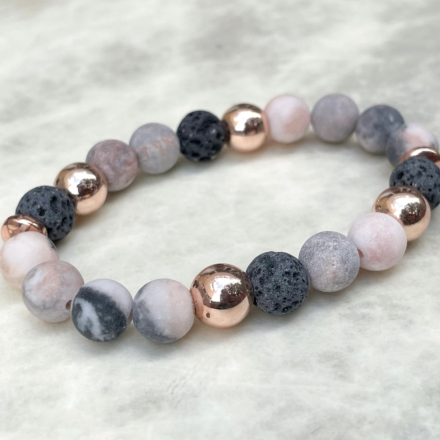 Beaded bracelet with gray, pink, and rose gold stones on a light gray background
