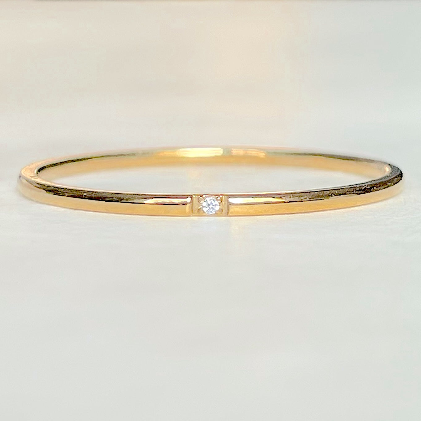 Close-up front view of delicate gold CZ band on a light gray background
