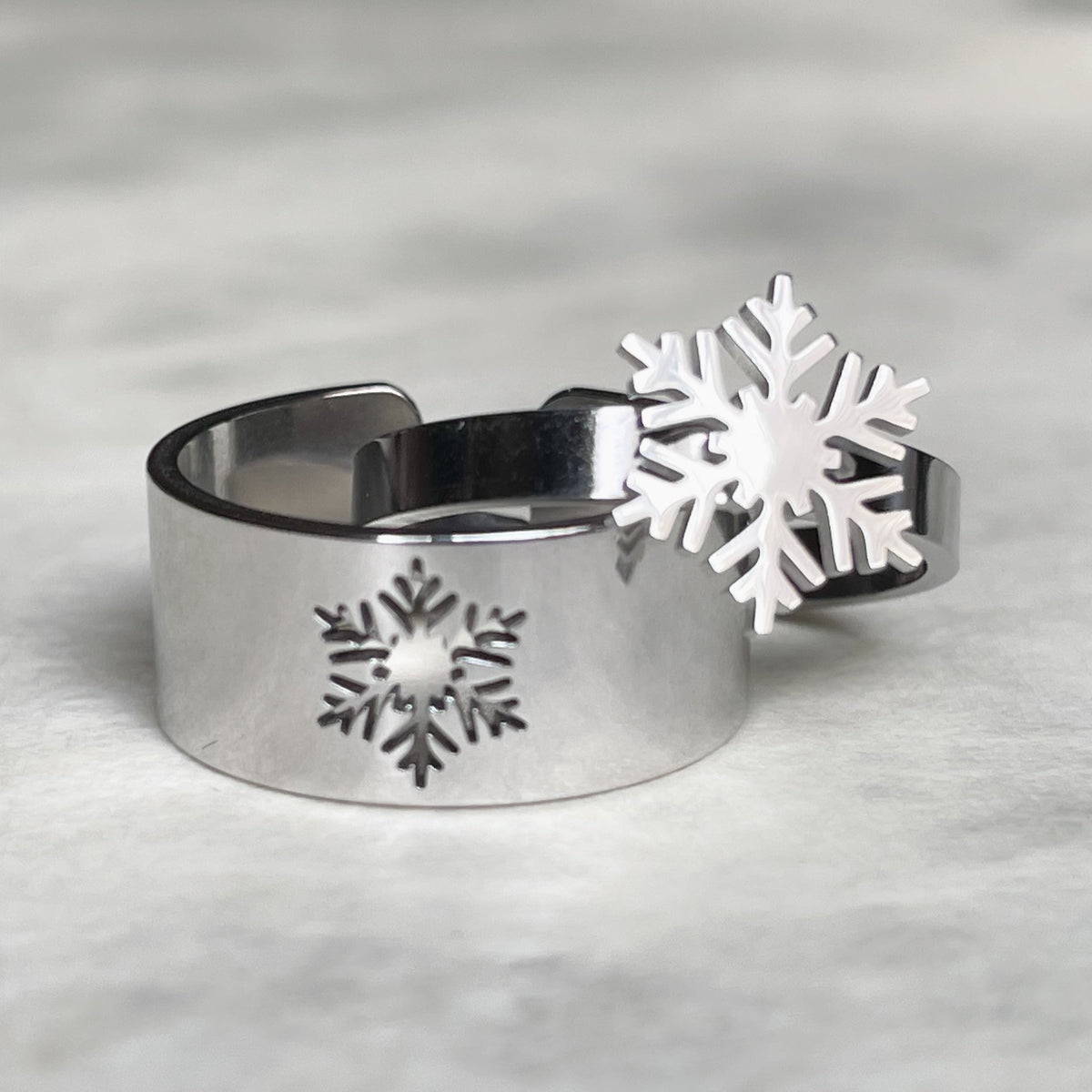 Two silver rings with snowflake design on a gray background