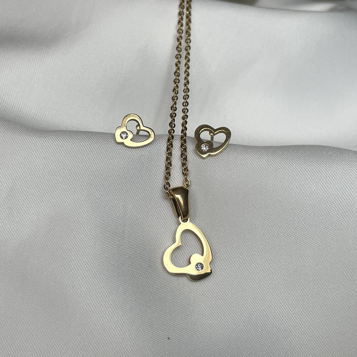 Front view of heart-shaped jewelry set on a gray fabric background