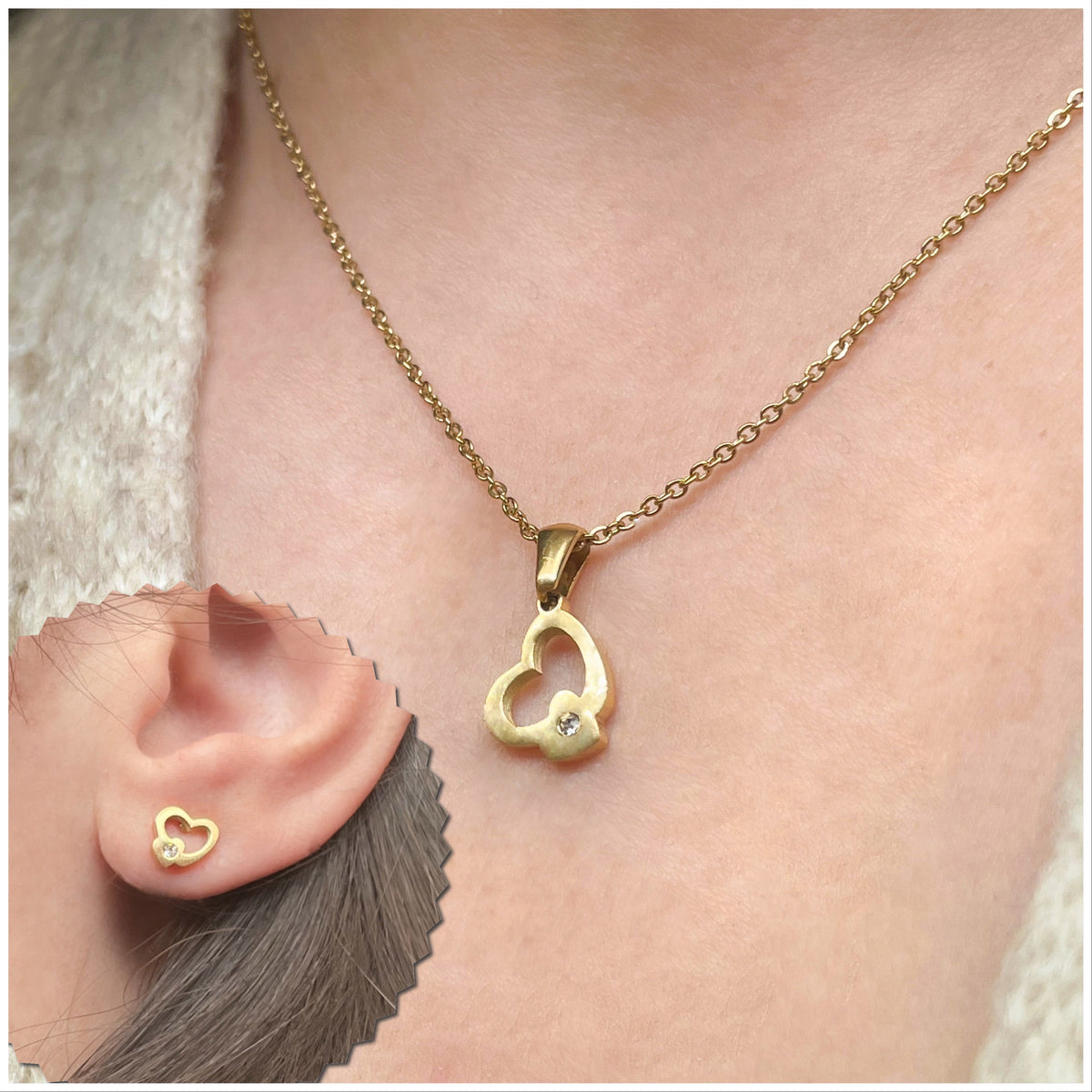 A gold-colored stainless steel jewelry set, including a small heart-shaped pendant and a chain, with a close-up inset showing the small CZ accent of the pendant and studs