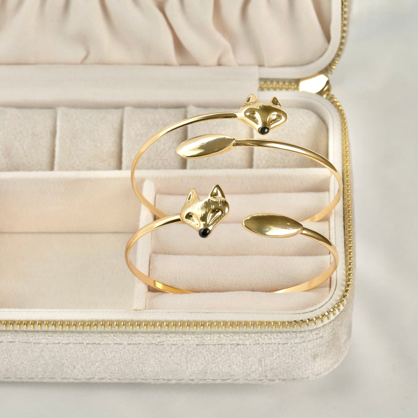 One small and one large gold cuff bracelets with fox designs on a jewelry box