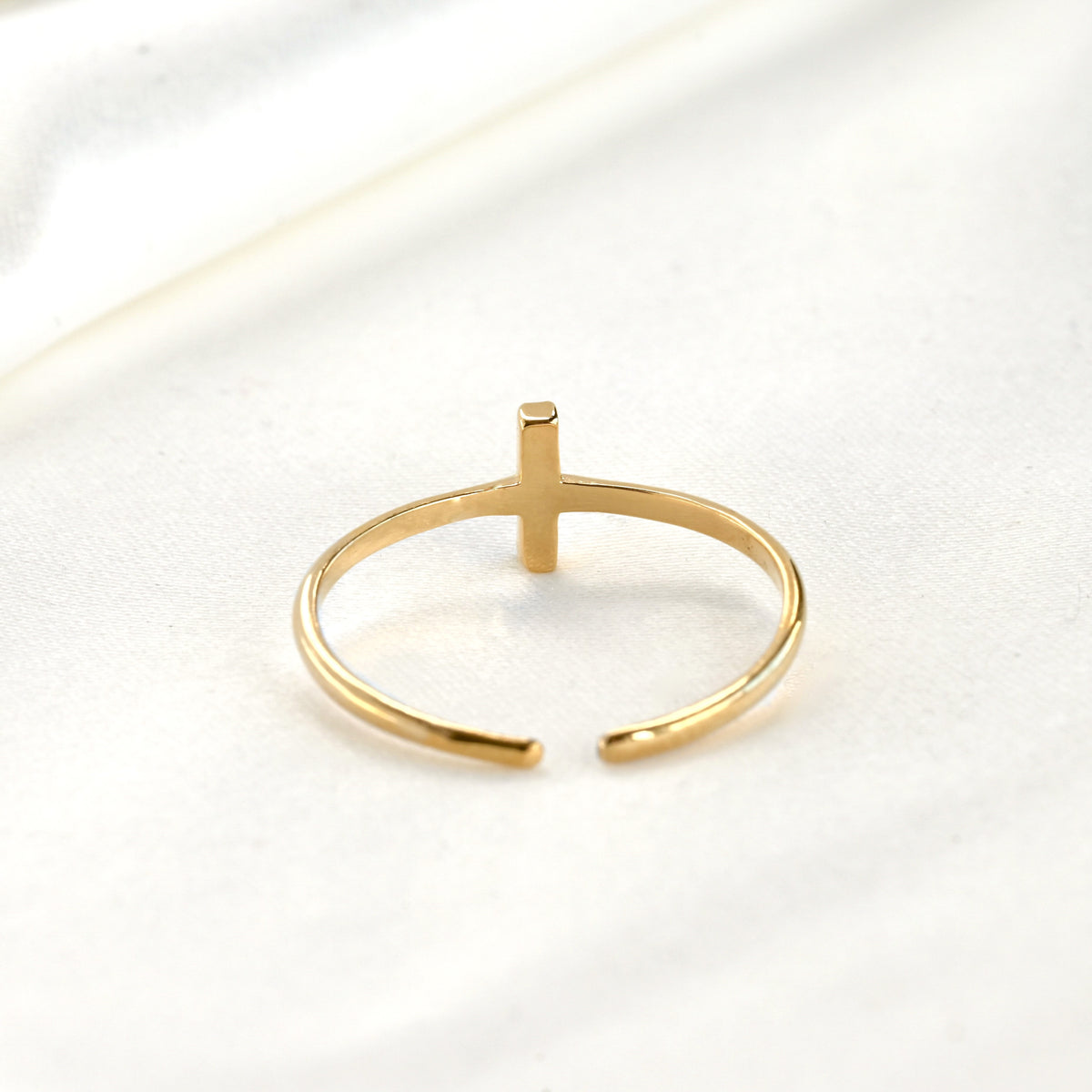 Back side view of gold ring with a vertical bar and adjustable open design on a white background