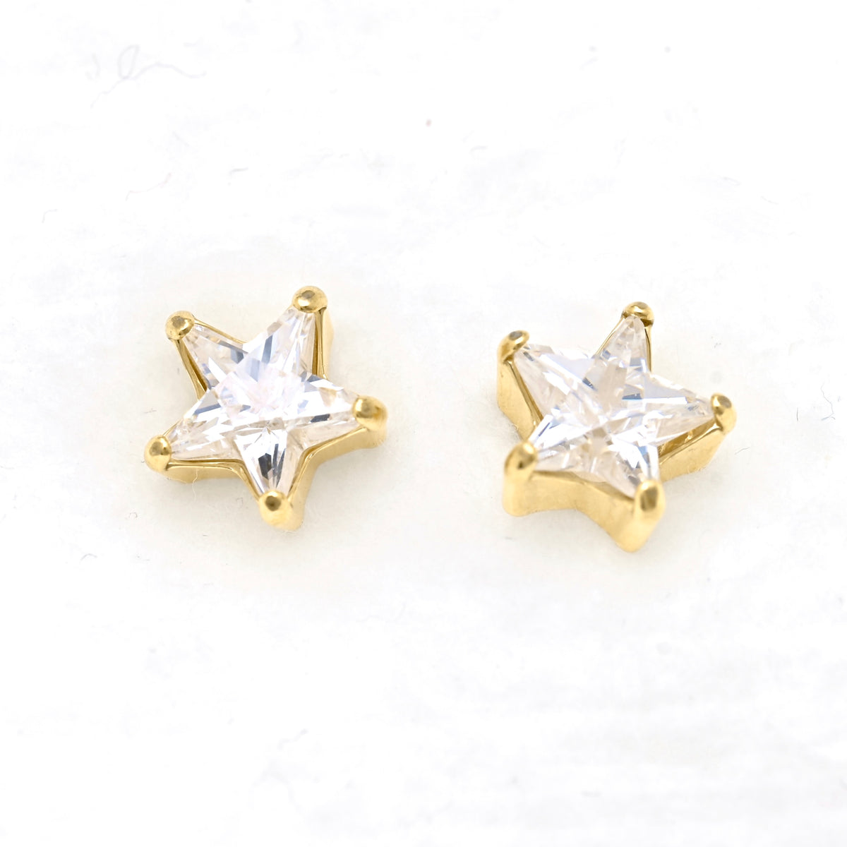 A pair of gold star-shaped stud earrings with star -shaped CZ, displayed on a clean white background.