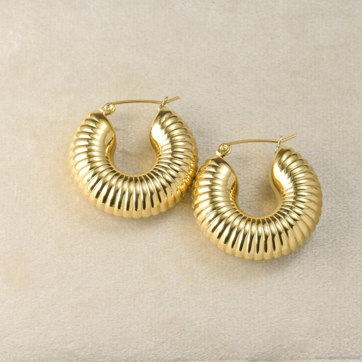 Textured Gold hoop earrings on a beige background