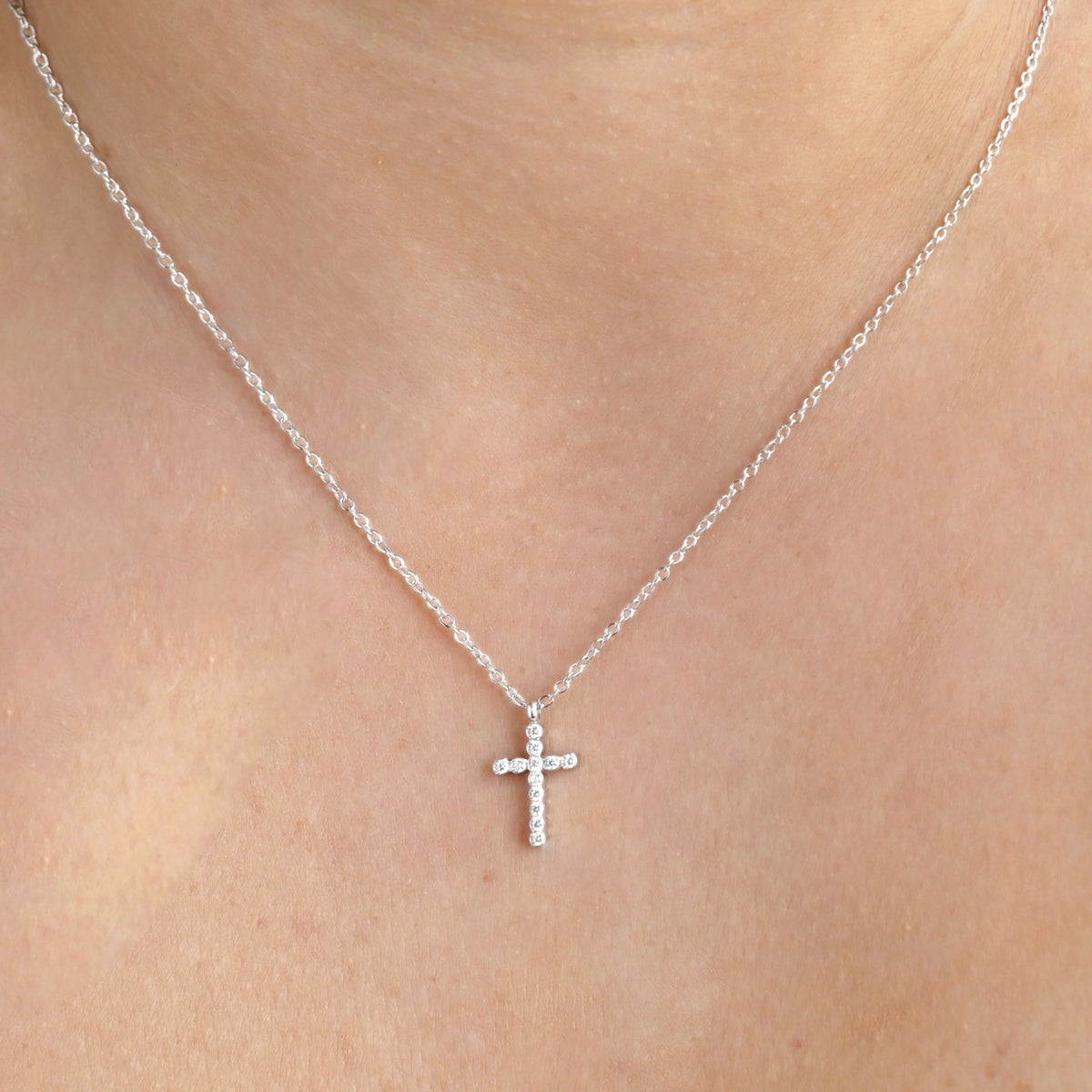 Front view of silver cross necklace on a person's neck