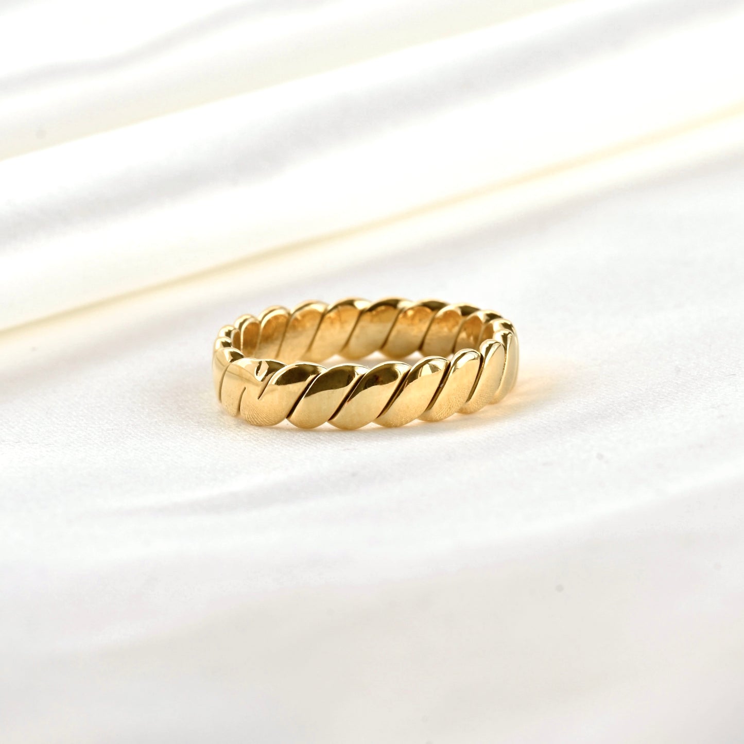 Close-up view of braided gold ring on a white background
