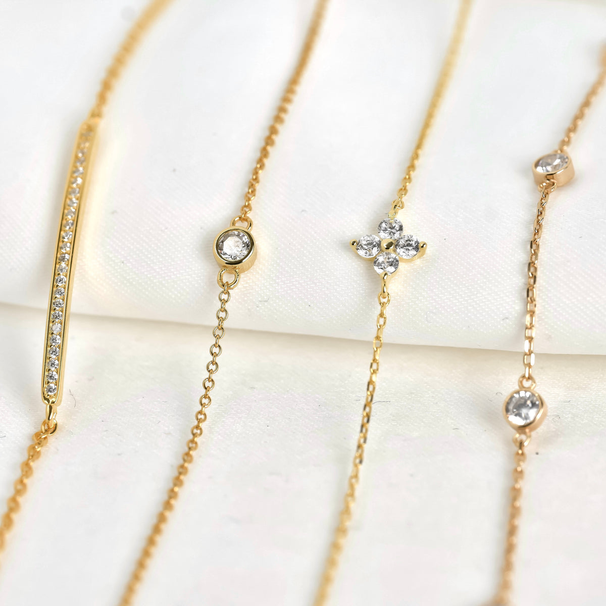 Front view of gold bracelets with flower and bar details on a white background
