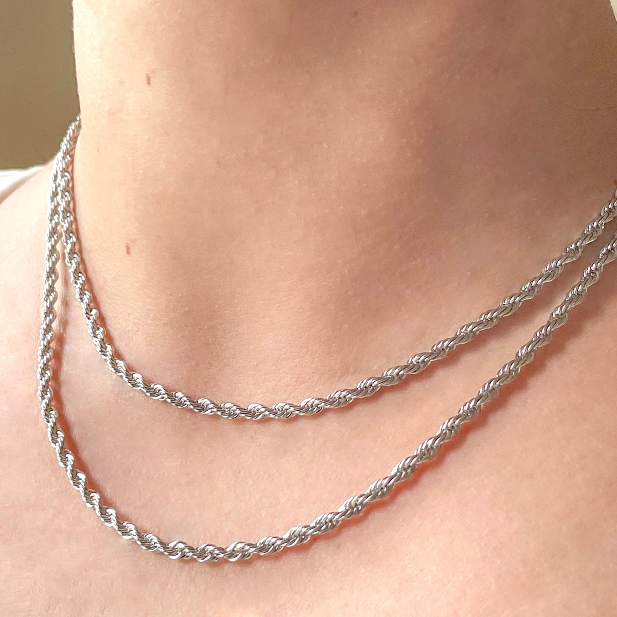 Angled front view of person wearing double layered silver rope chain necklaces