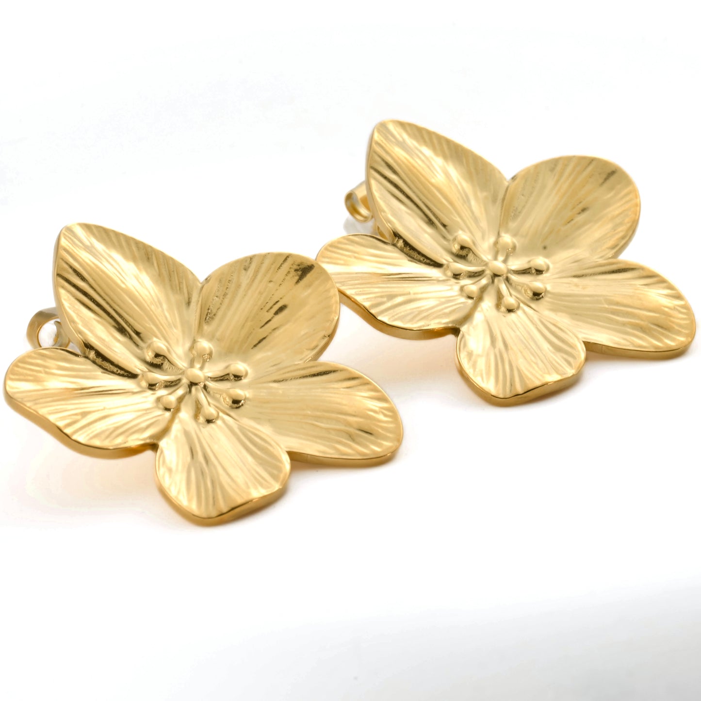 Pair of gold flower-shaped earrings on a white background from a different angle
