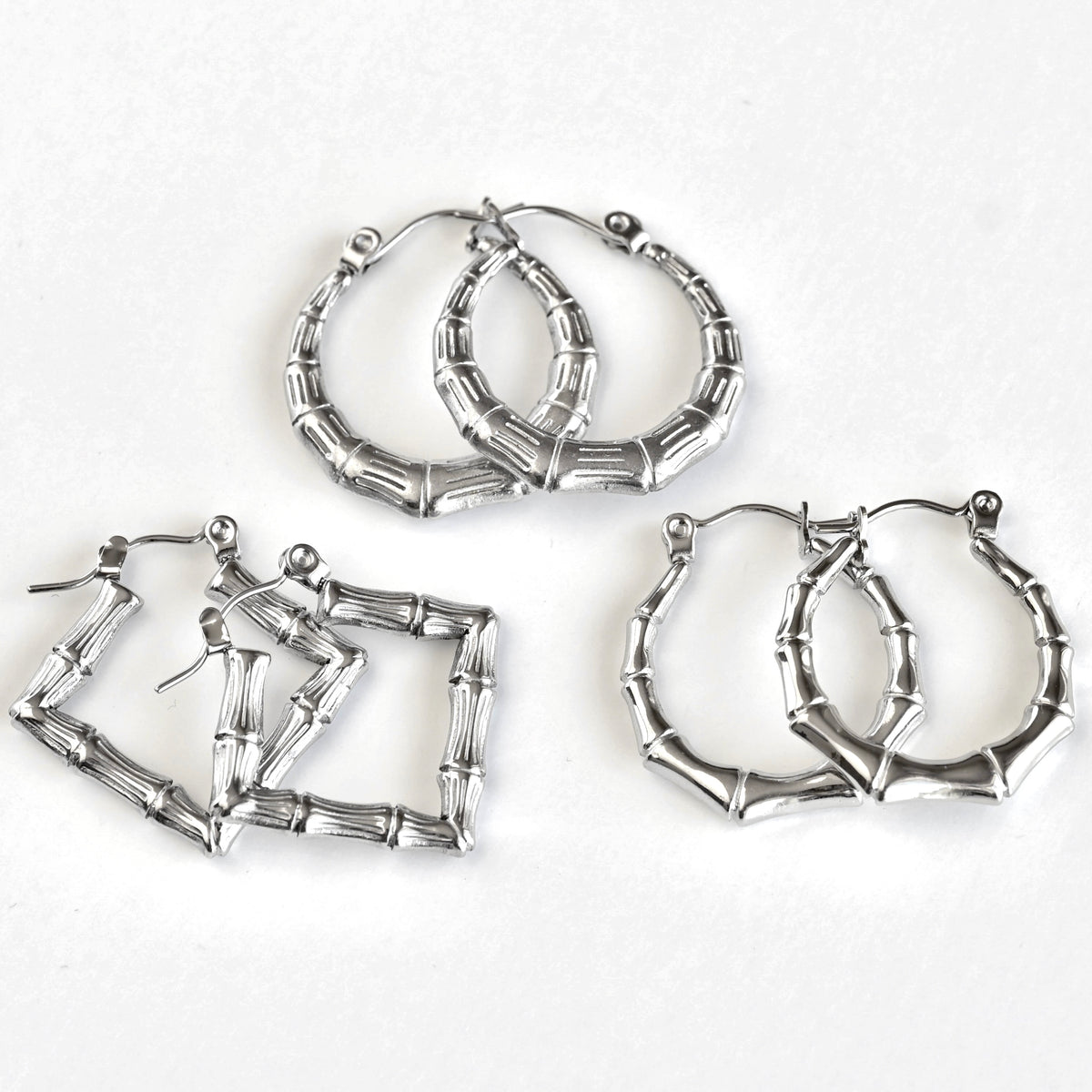 Three pairs of silver-toned hoop earrings with a bamboo branch link design, arranged on a plain white background.