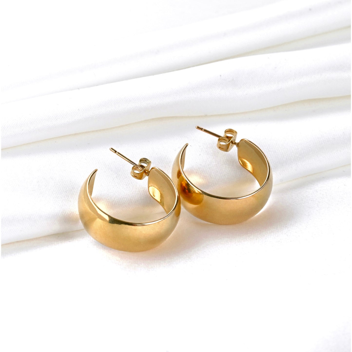 Chunky gold C hoops with posts and butterfly backs on a white background