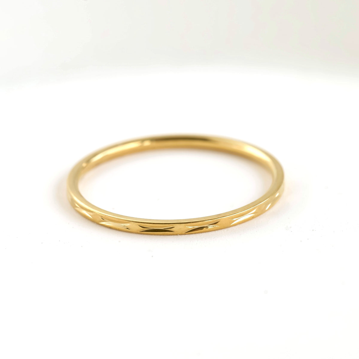 Textured dainty thin gold ring on a white background