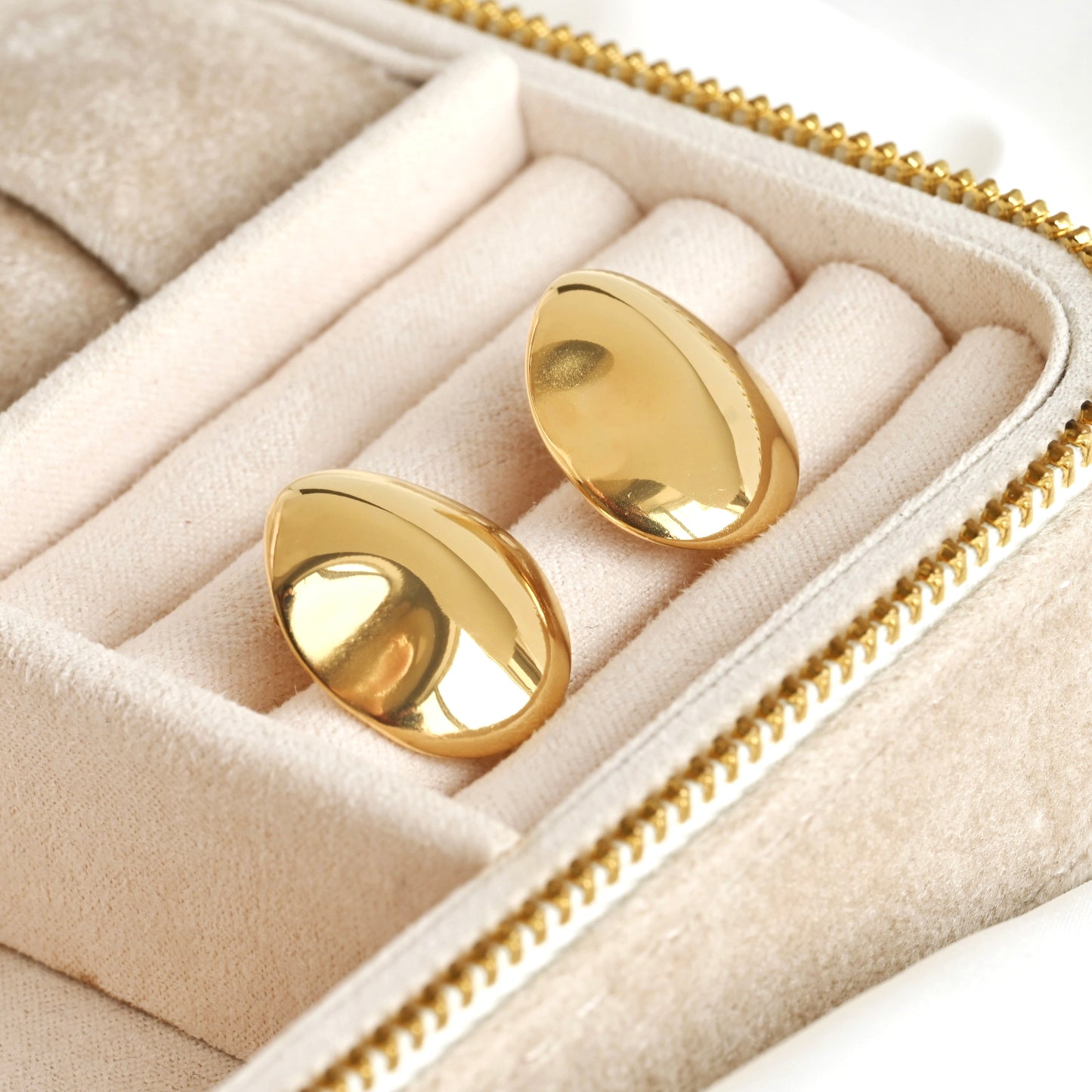 Gold oval drop earrings in a jewelry box on a white background