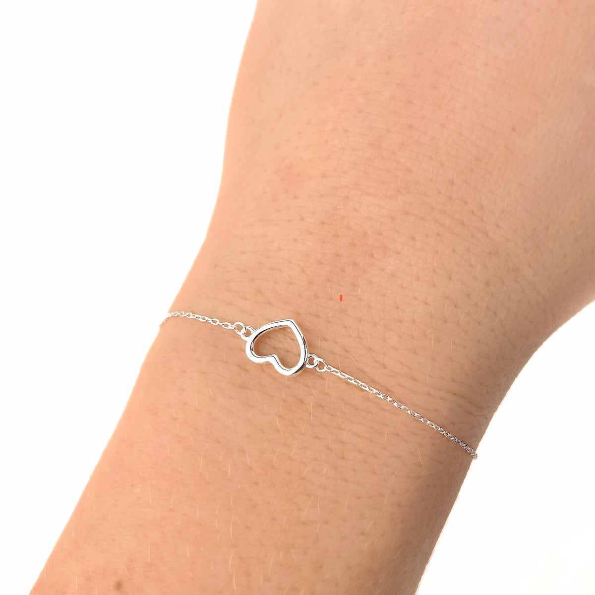 Silver heart-shaped bracelet on a wrist against a white background