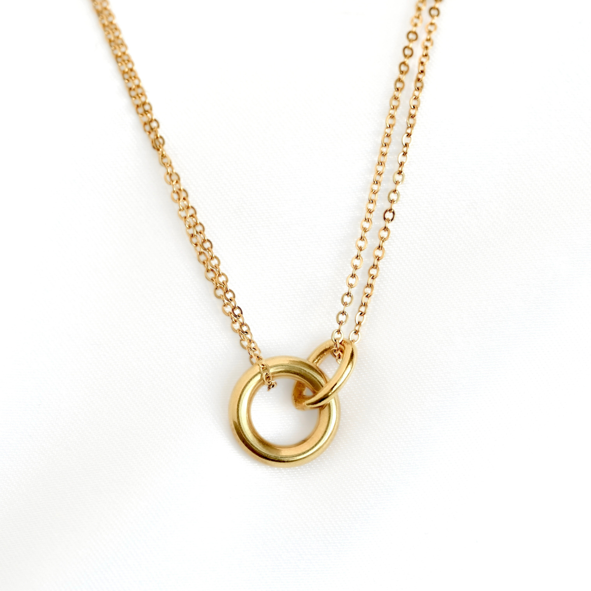 A layered gold chain necklace featuring two interlocking open circular rings, photographed against a clean white background.