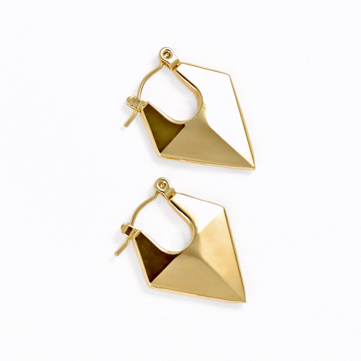 A pair of gold geometric hoop earrings with faceted triangular drop pendants, shown on a clean white background.