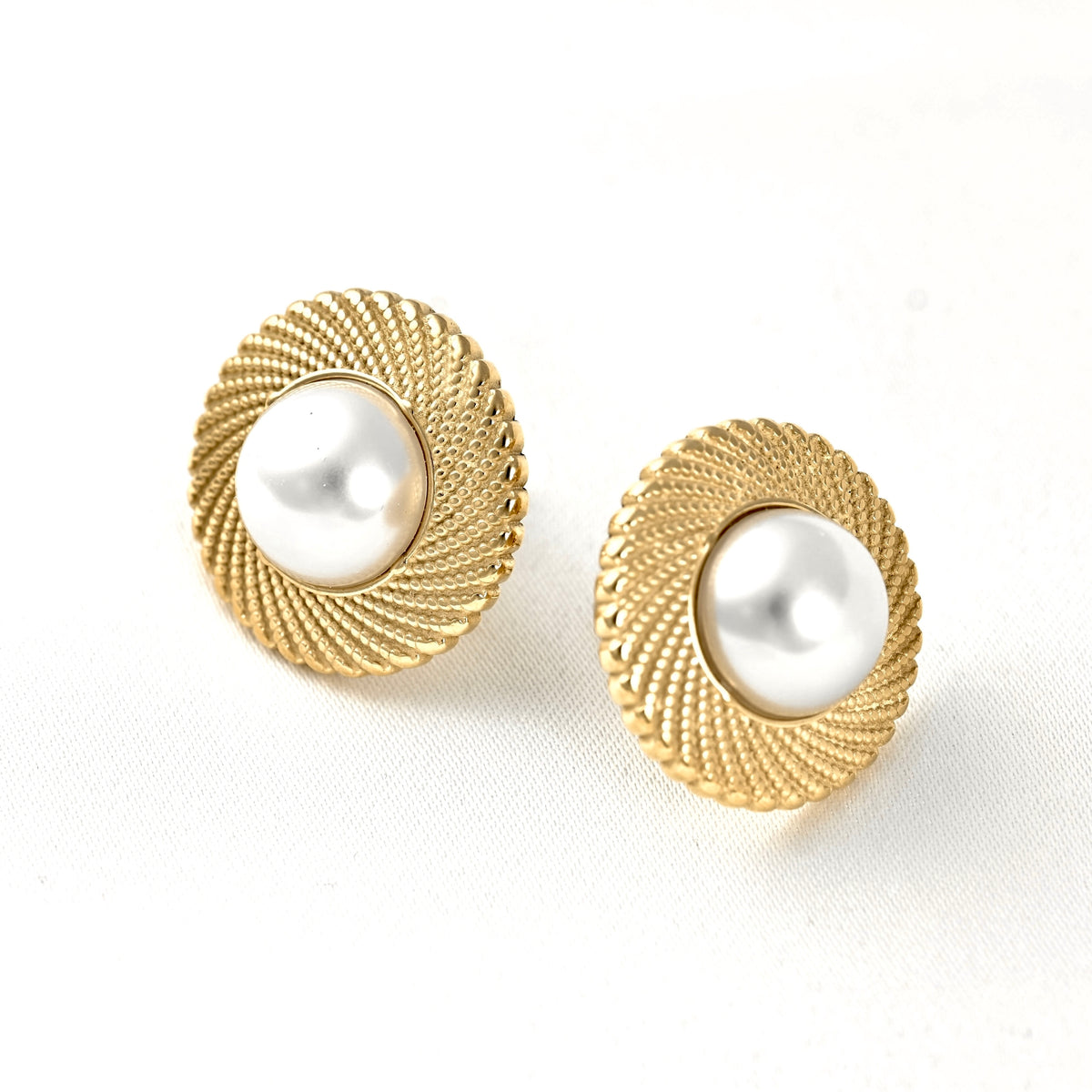 A pair of gold-toned round stud earrings with a textured rope-like border and a smooth white pearl center, shown on a clean white background.