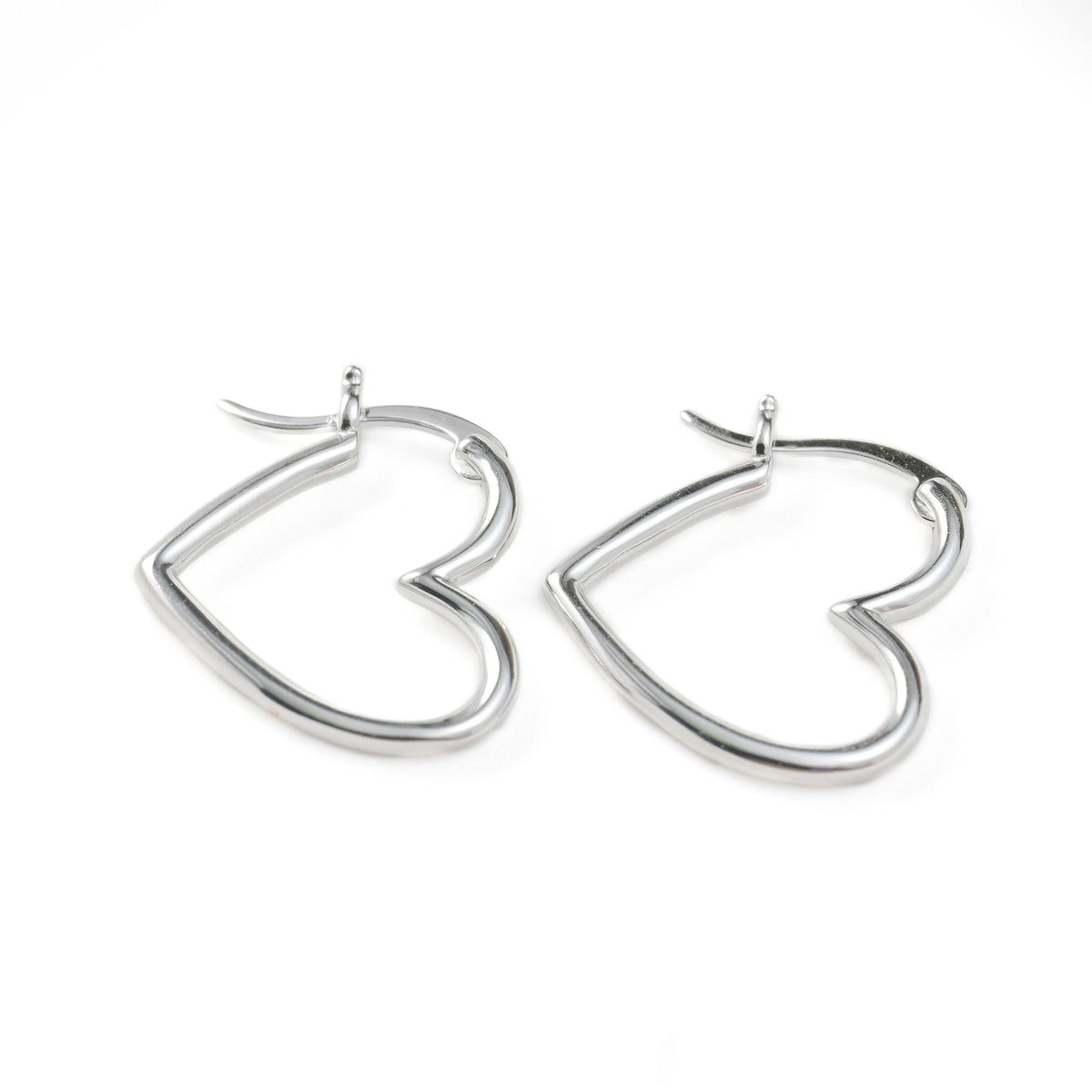 Heart-shaped silver hoop earrings on a white background