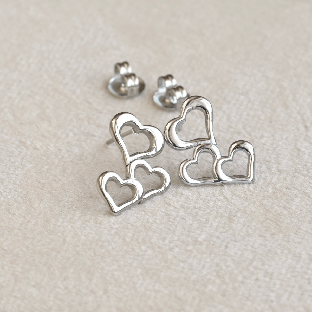 Silver heart cluster dangle earrings on a light gray background