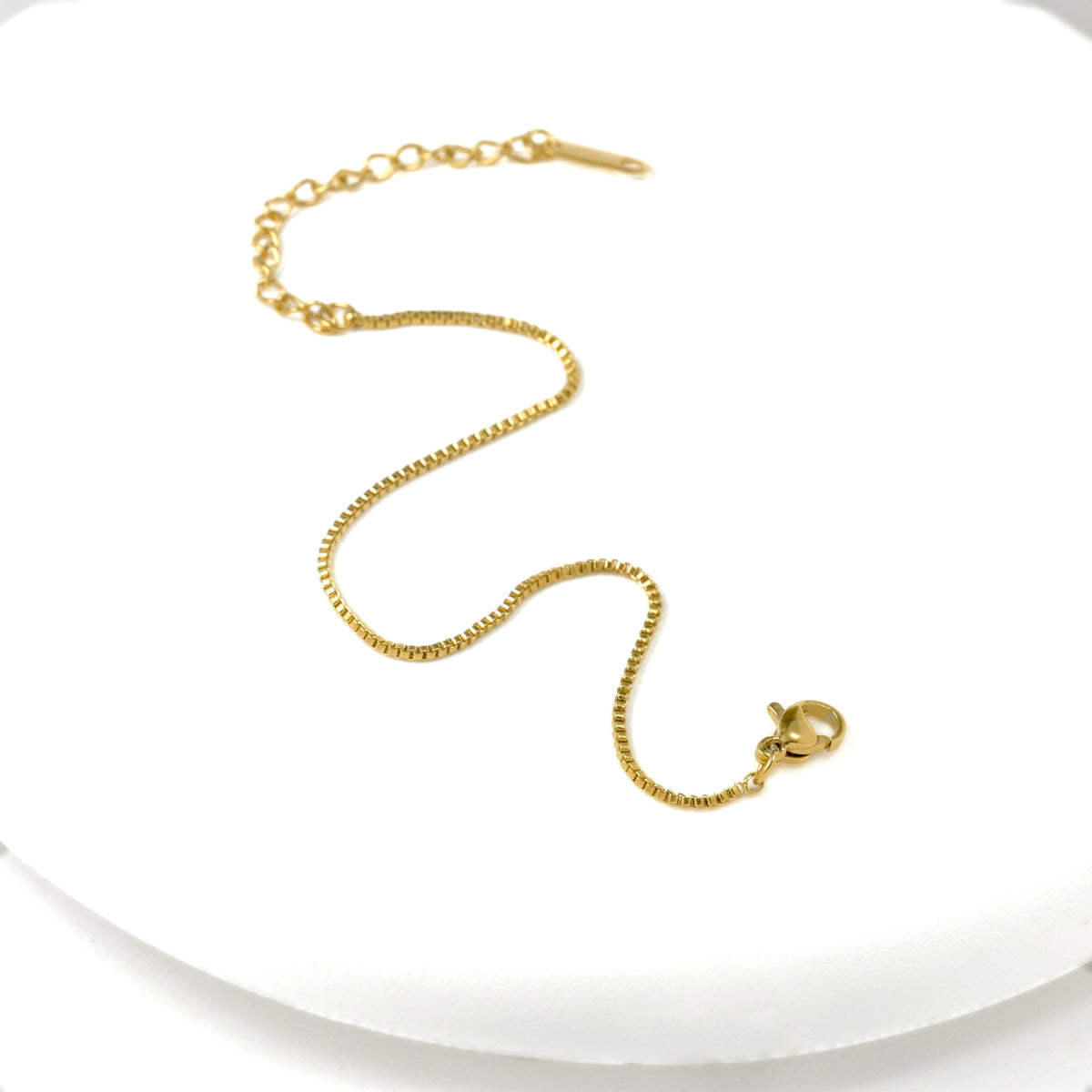 Gold box chain bracelet with an extender on a white background