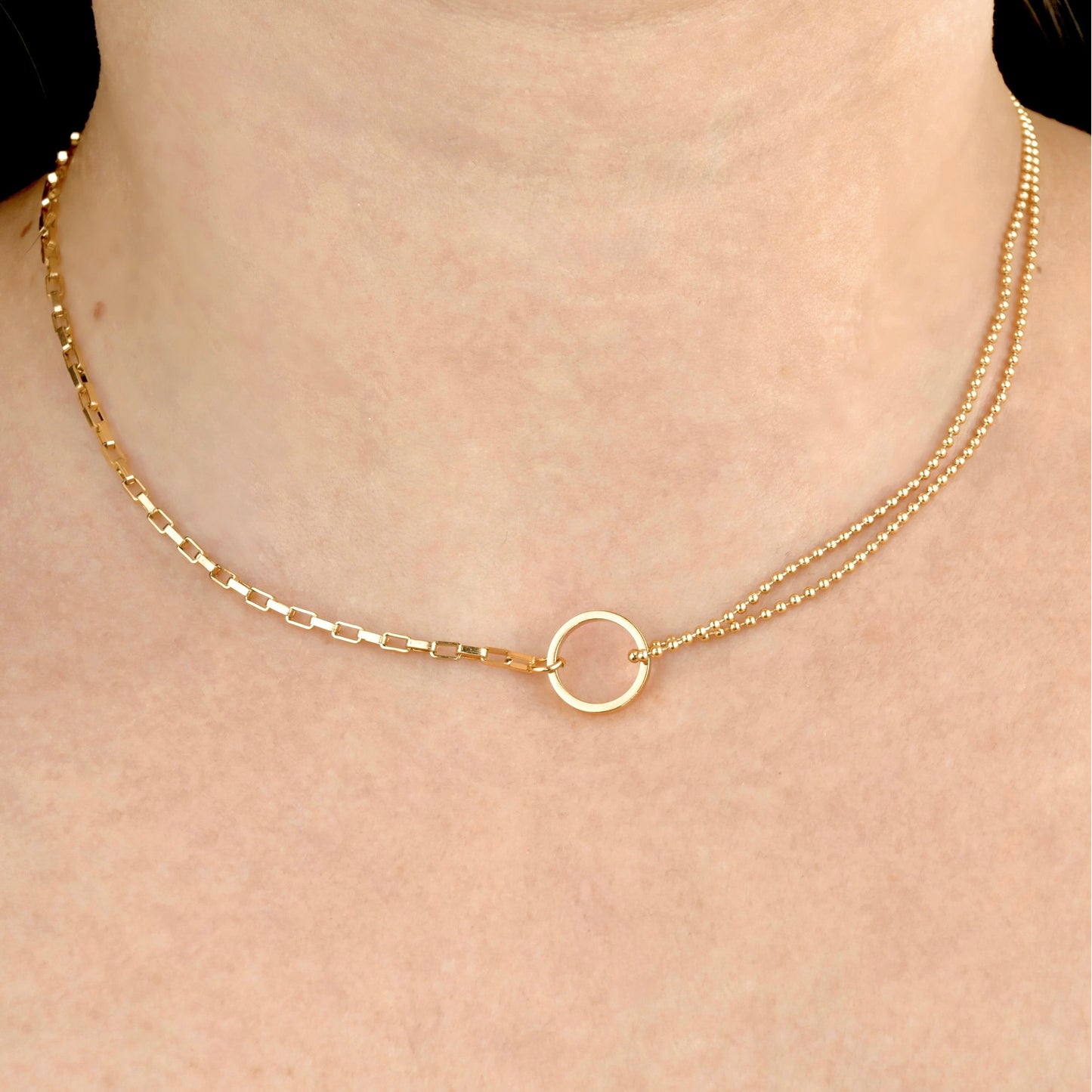 Gold circle link necklace with a bold rectangular chain and double layered ball chain on each side on a person's neck