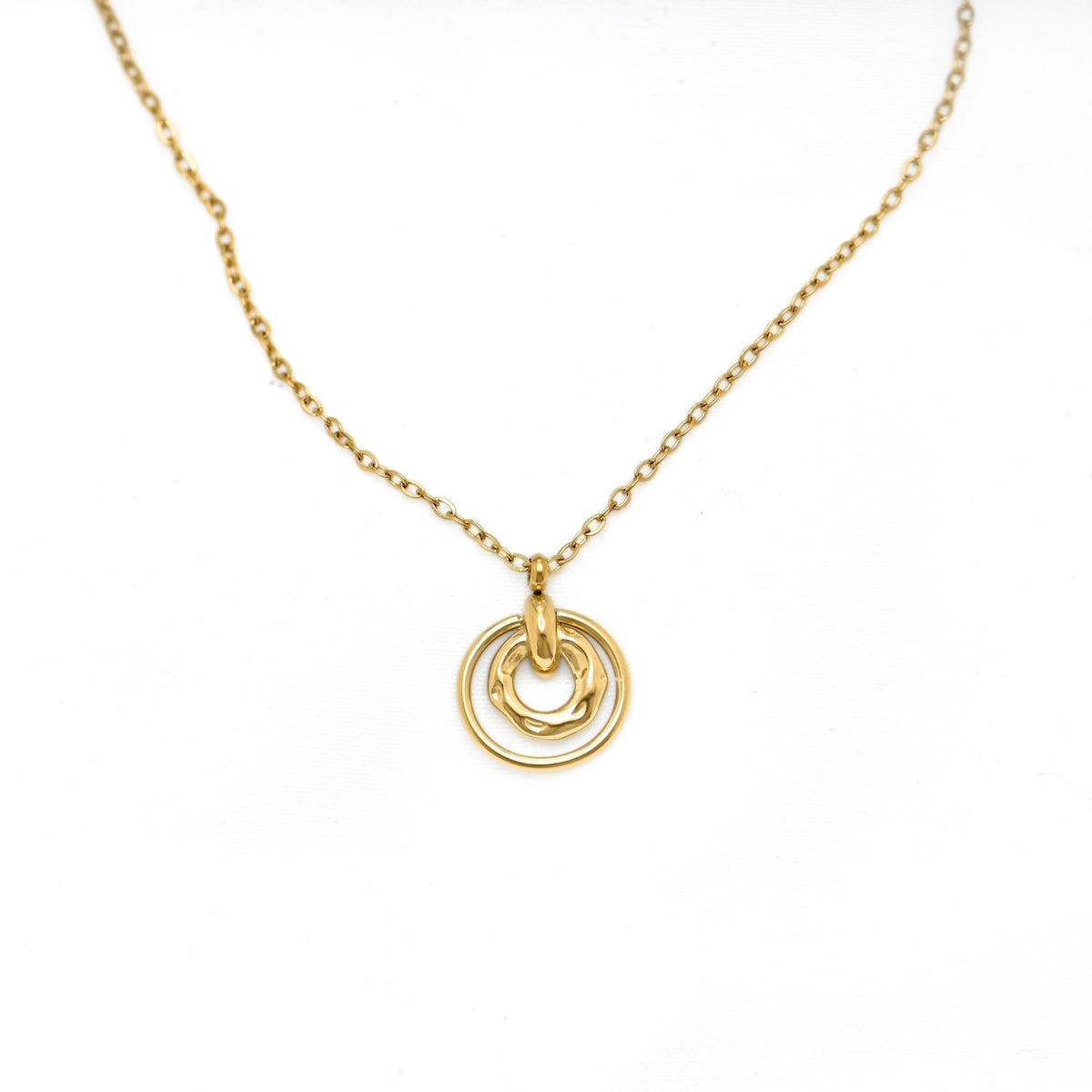A delicate gold chain necklace featuring a double-ring pendant with one smooth ring and one textured, organic-shaped ring, displayed on a clean white background.