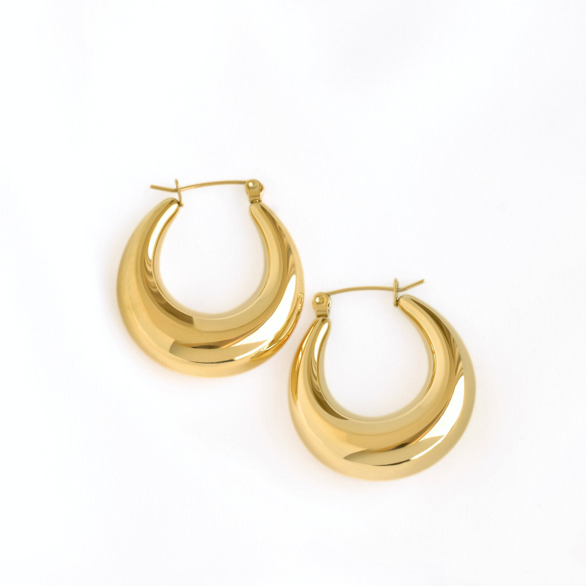 A pair of polished gold crescent-shaped hoop earrings on a clean white background.