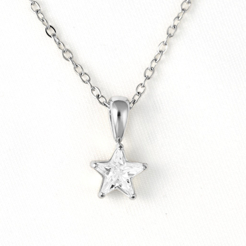 A silver star-shaped pendant necklace with a clear faceted gemstone, suspended from a delicate silver chain against a white textured background.