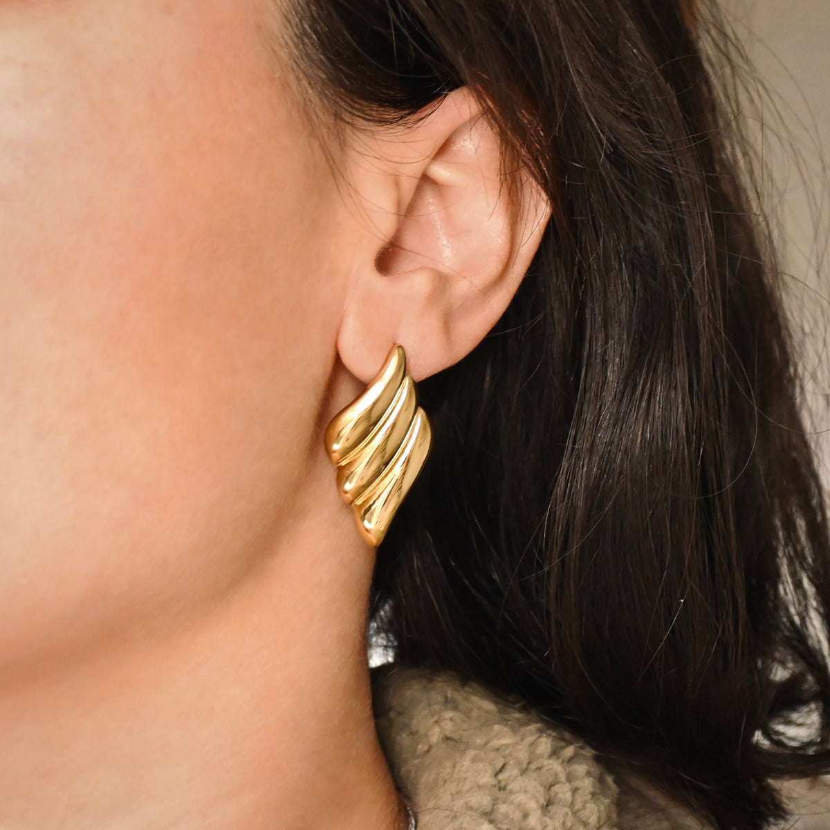 Large Gold rhombus earrings worn by a person with dark hair.