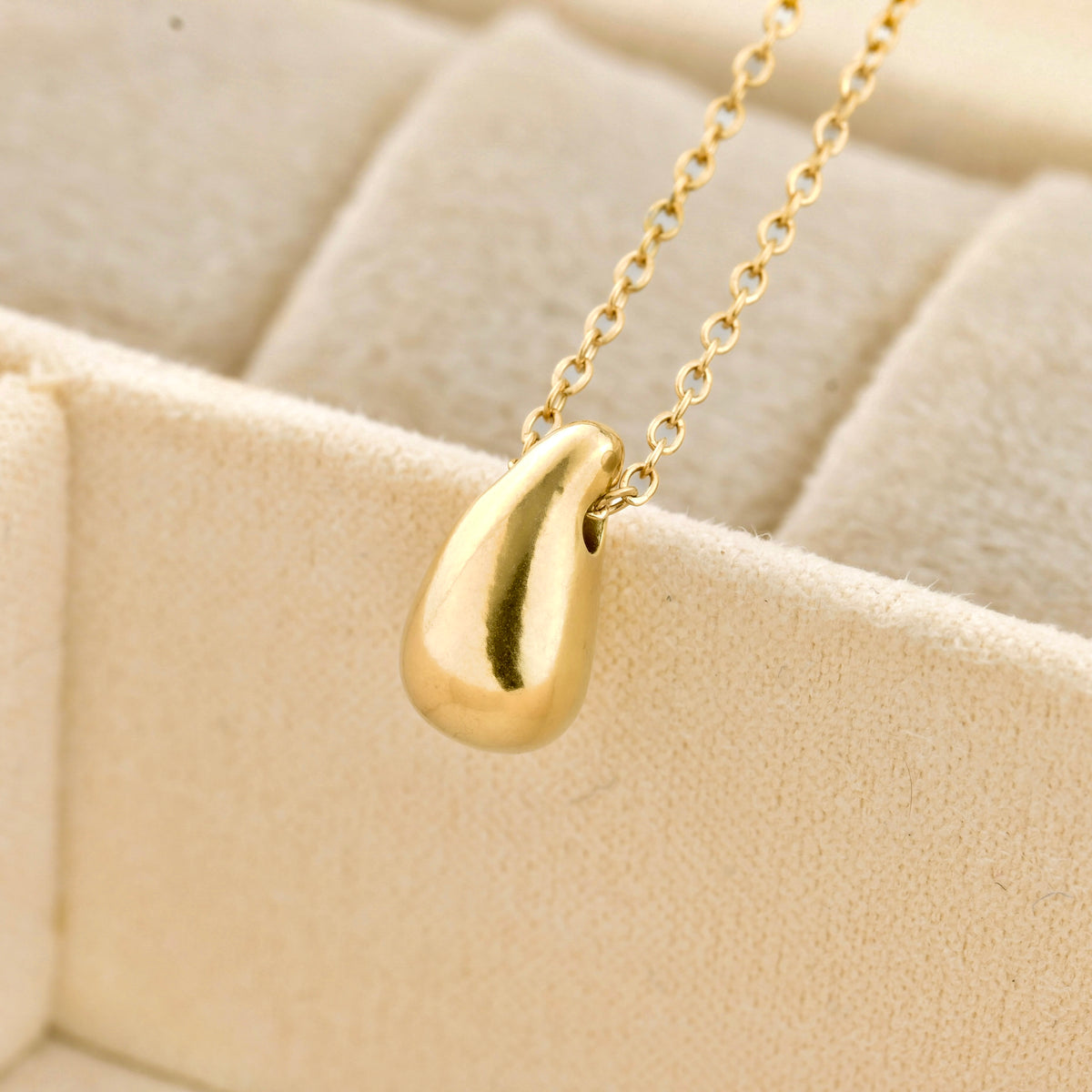 close up of teardrop-shaped pendant on a beige textured background