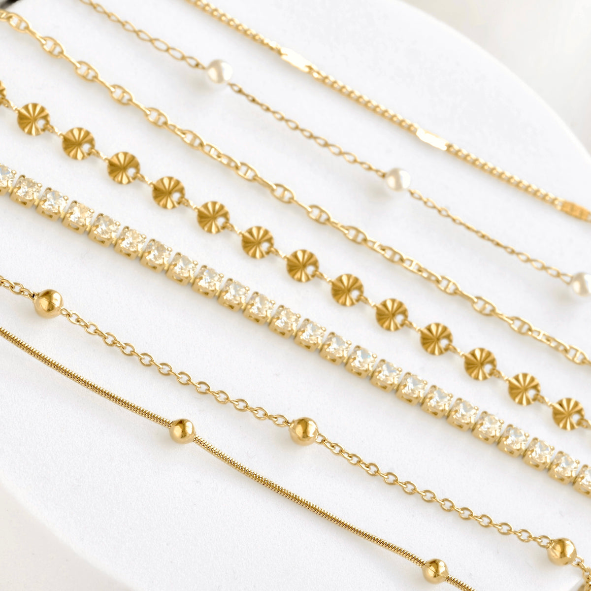 A close-up of delicate gold chain bracelets on white background