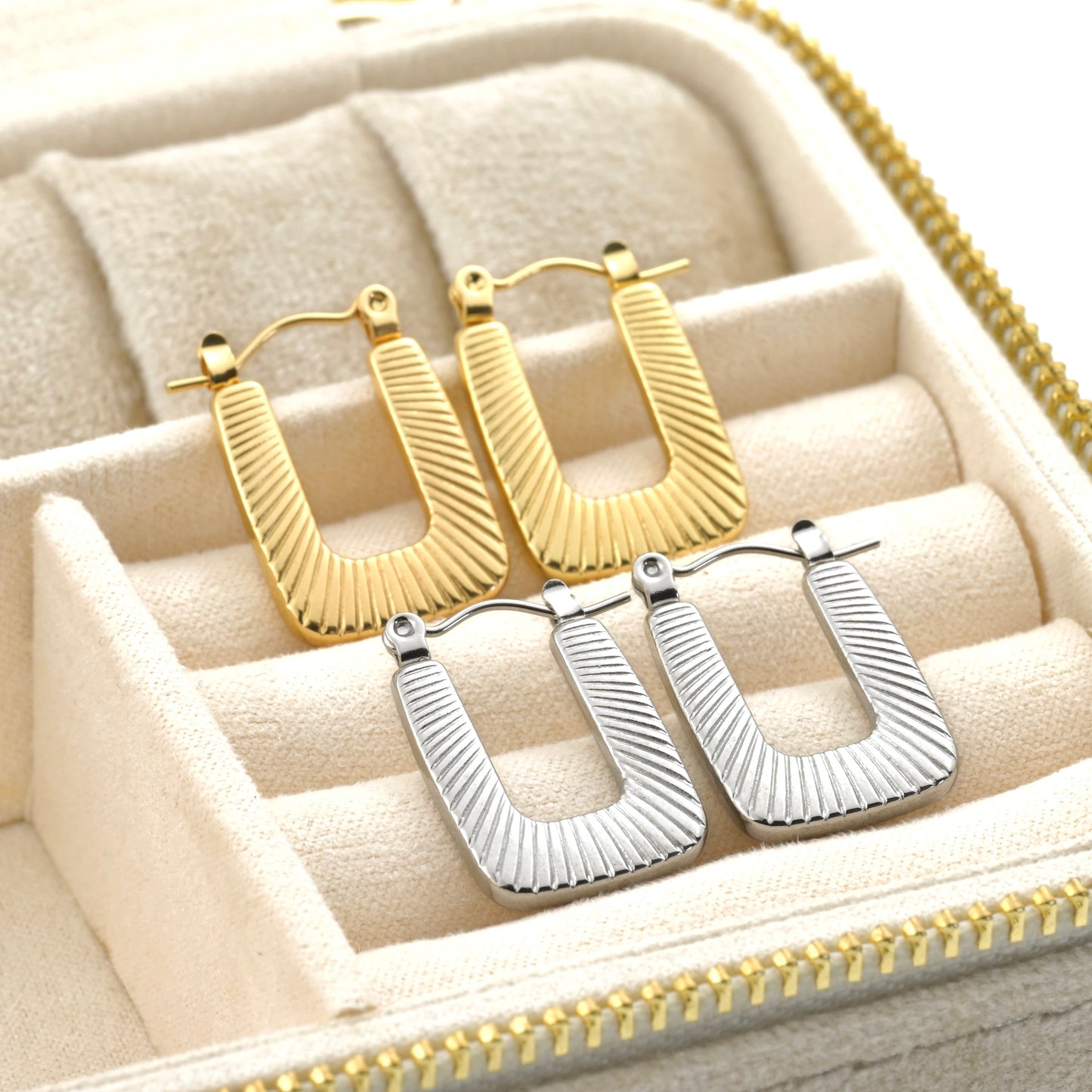 Gold and silver ribbed hoop earrings in a jewelry box