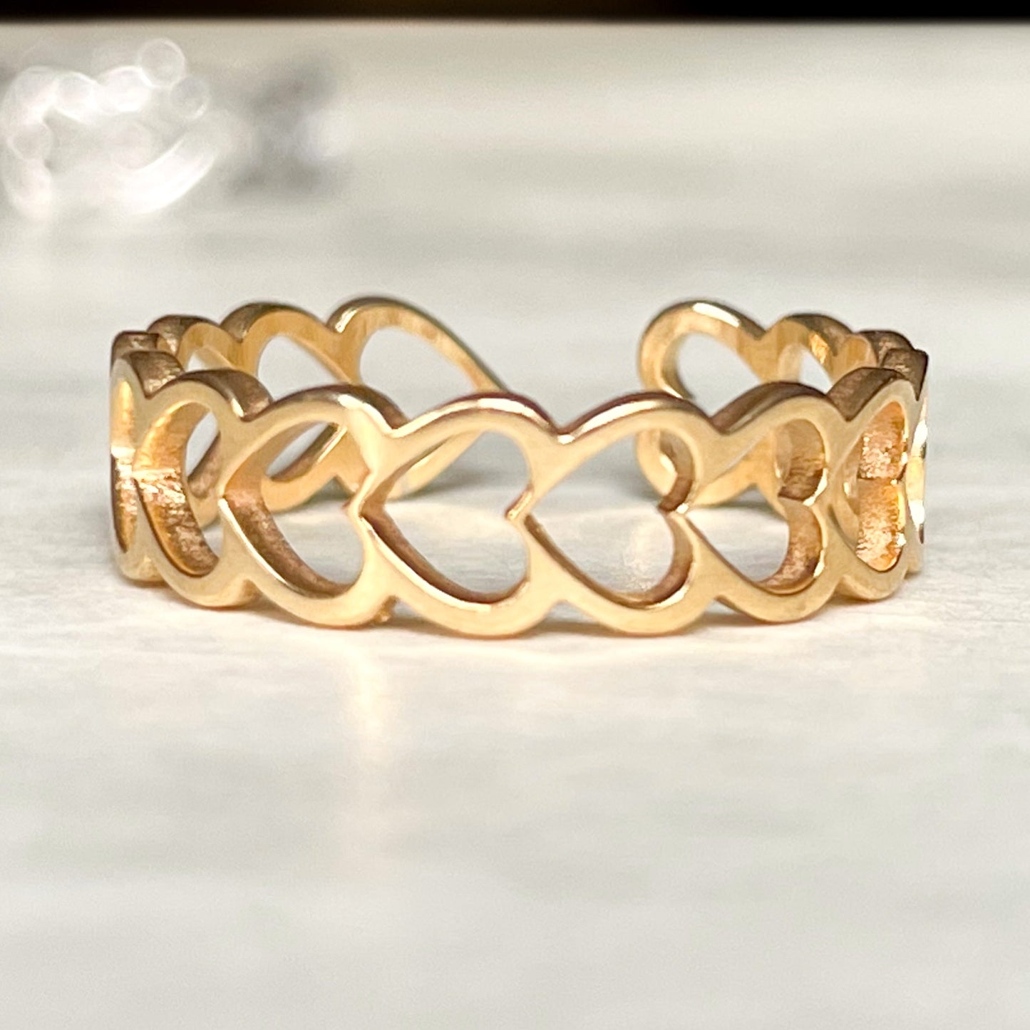 Gold heart link band with interlocking heart designs on a light background